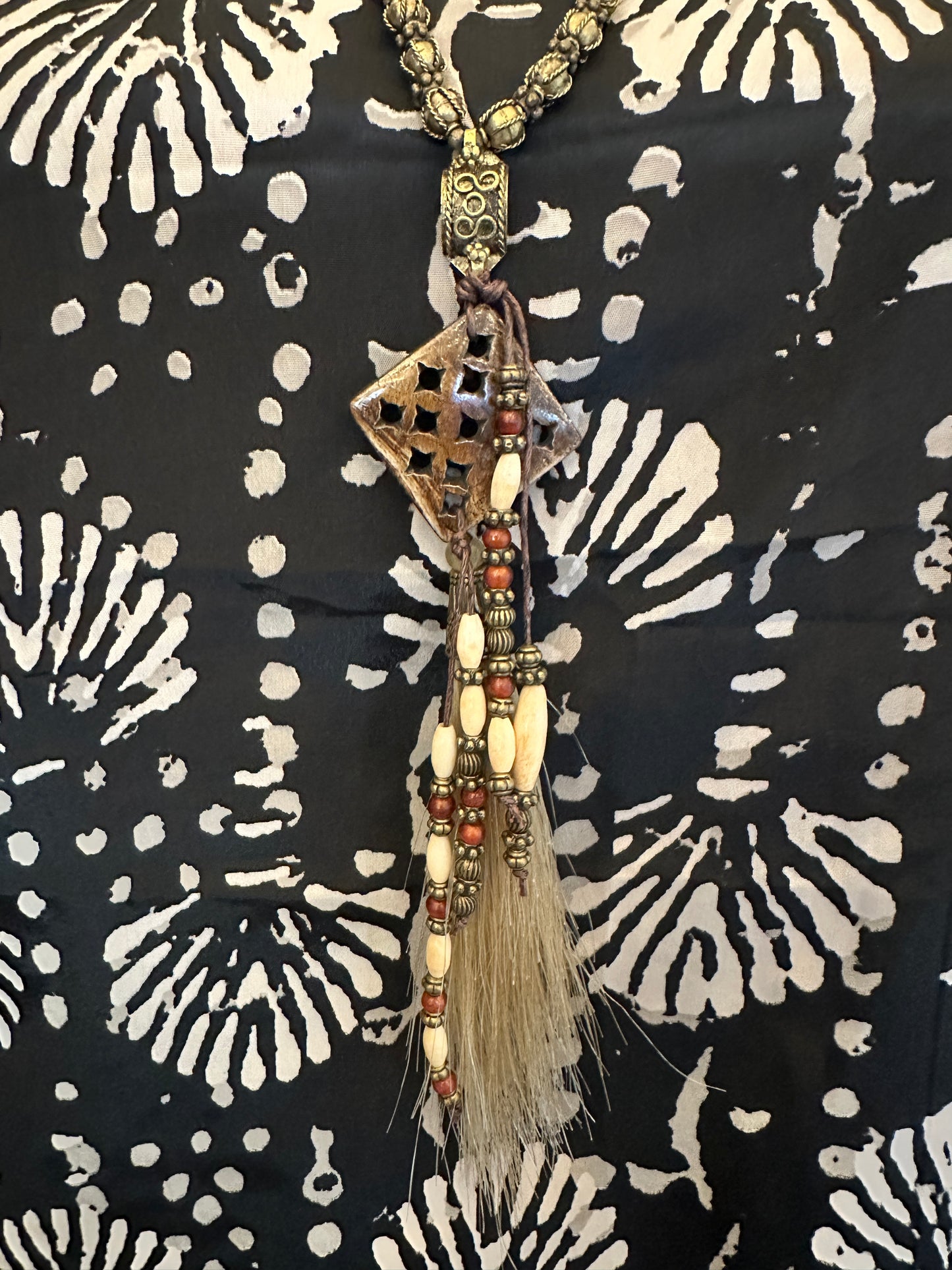 Necklace with geometric pendant and tassel.