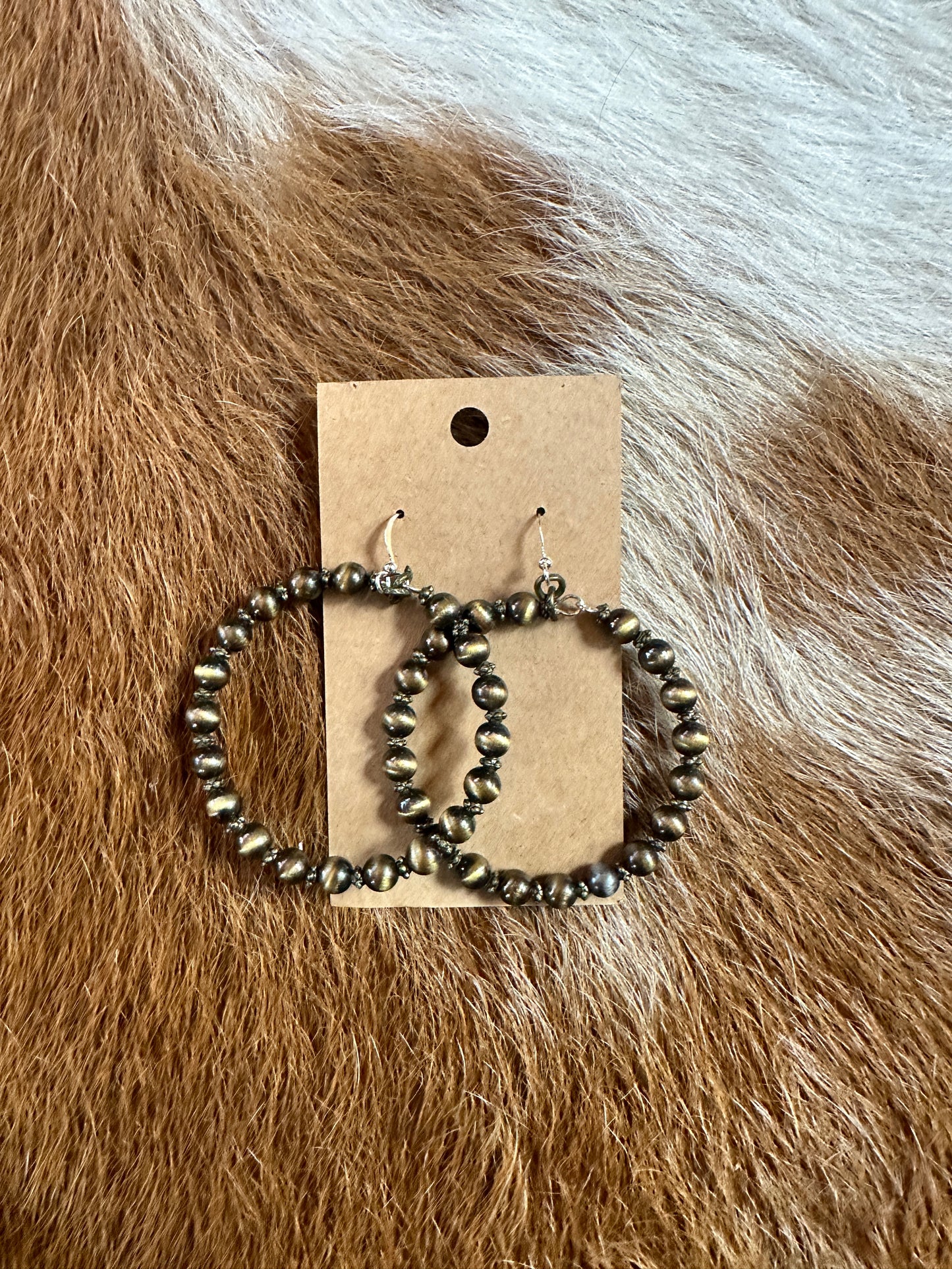 Hoop earrings with small beads on a brown background.