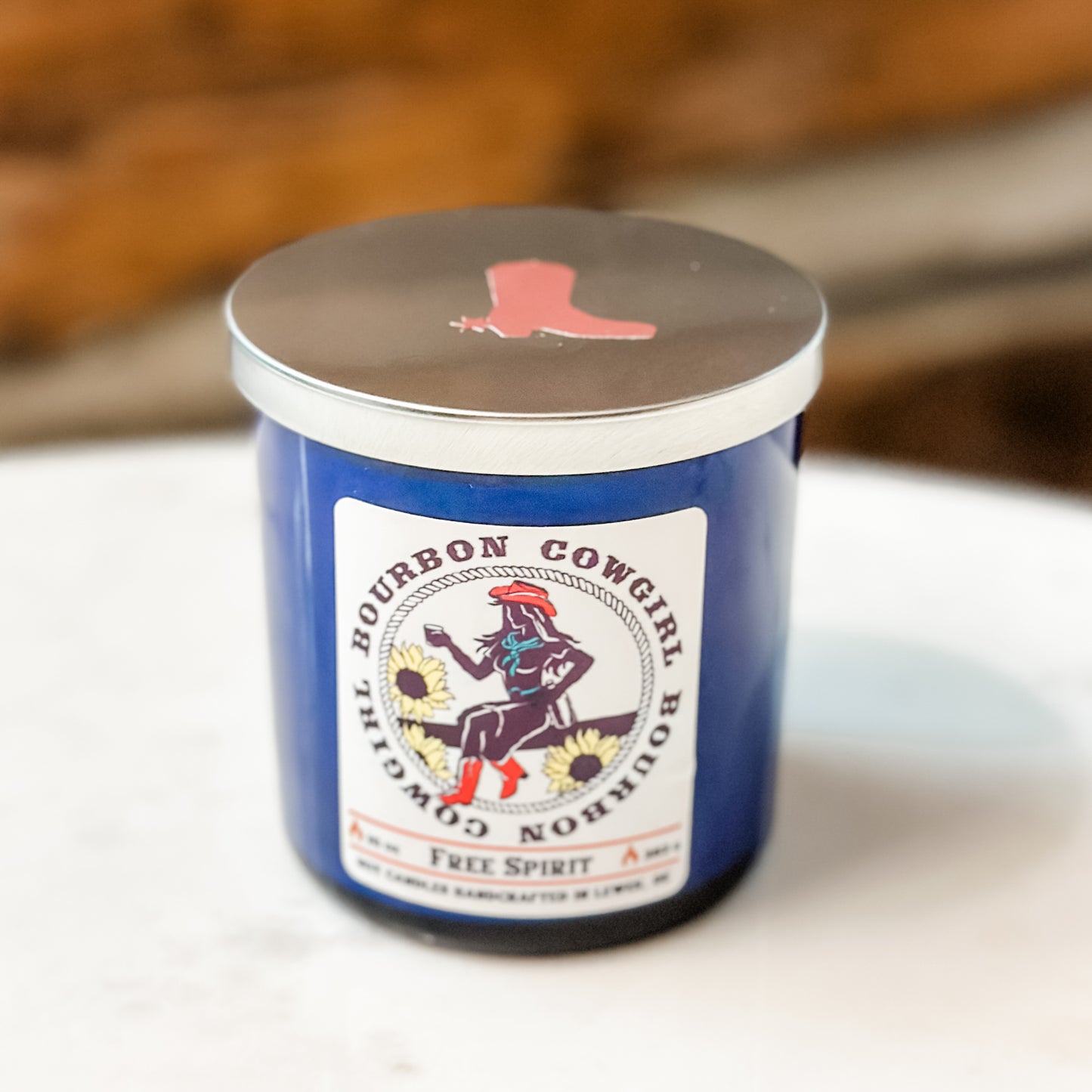 Blue candle with cowgirl label and silver lid.