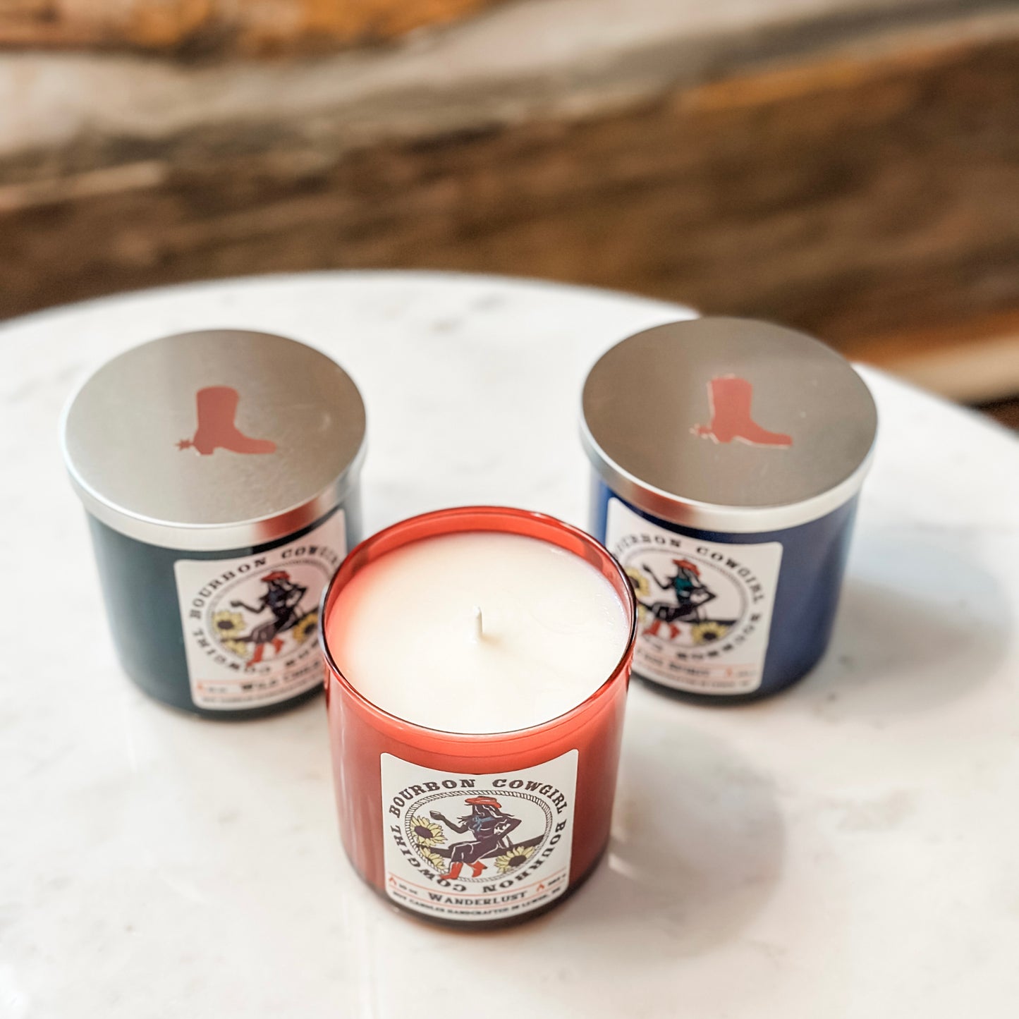 Three scented candles with cowboy boot lids.