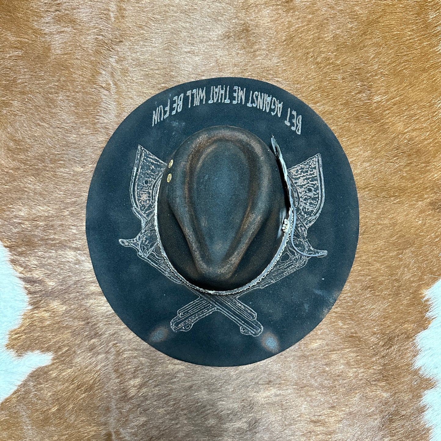 Dark hat with graphic on cowhide background.