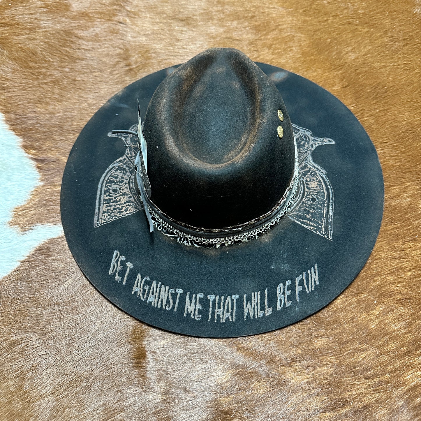 Dark hat with pistol design and text.