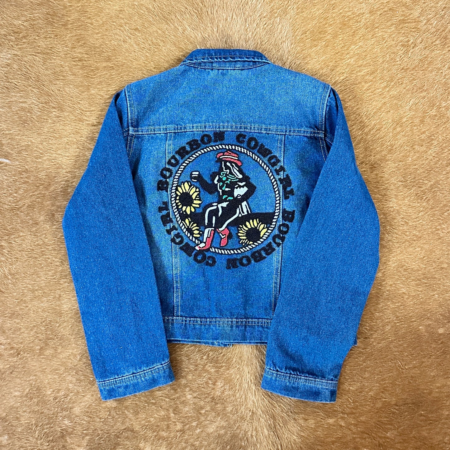 Blue denim jacket with embroidered back design.