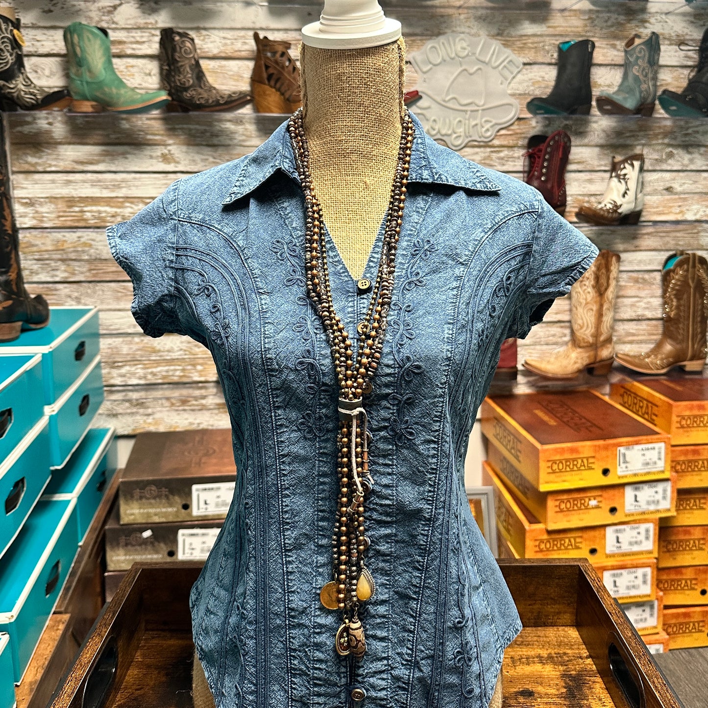 Blue denim shirt with long beaded necklace.