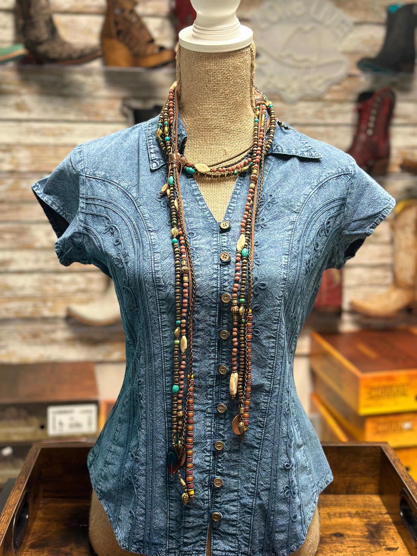 Blue denim shirt on a mannequin with layered necklace.