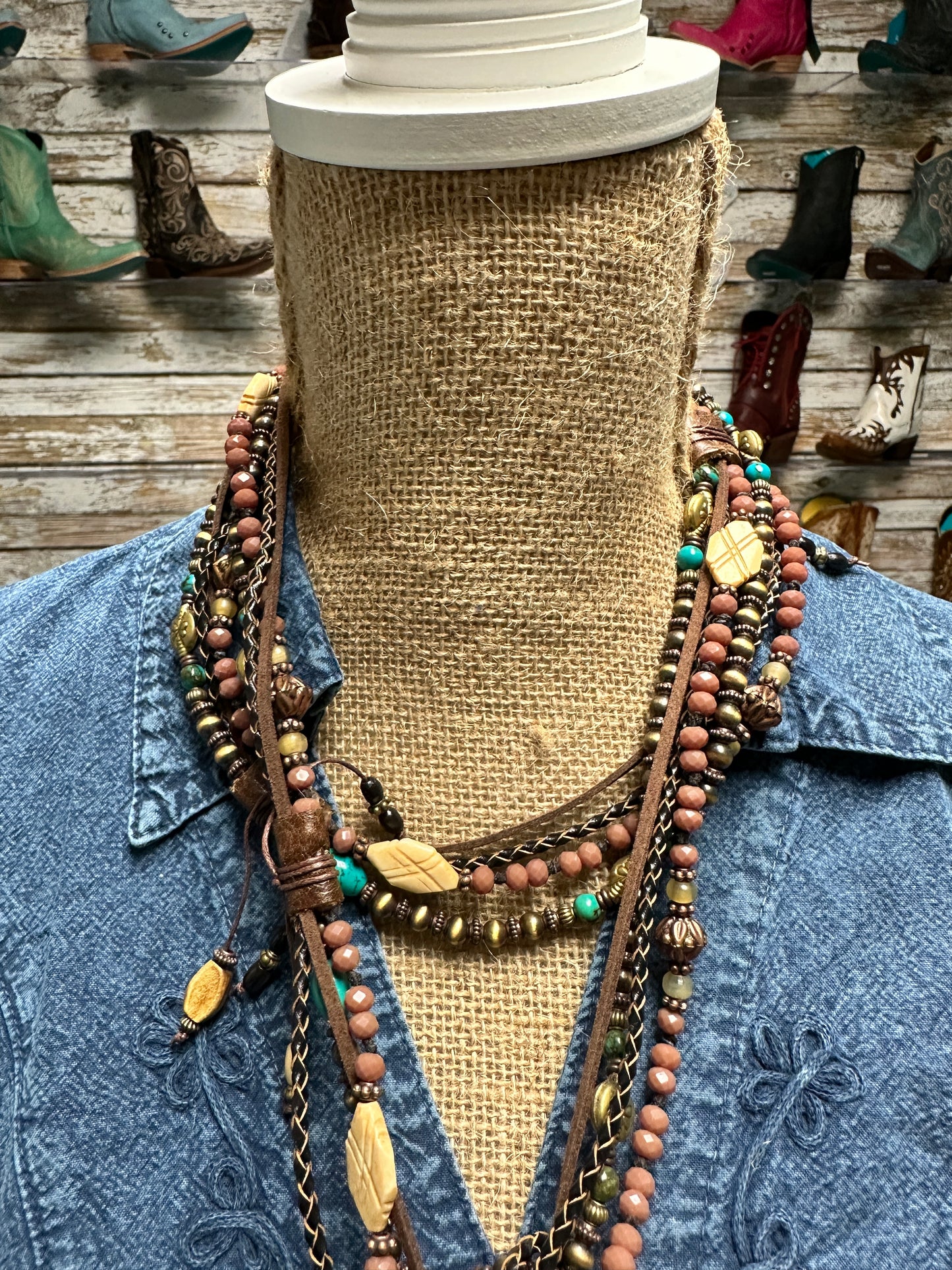 Mannequin wearing layered necklaces and denim shirt.