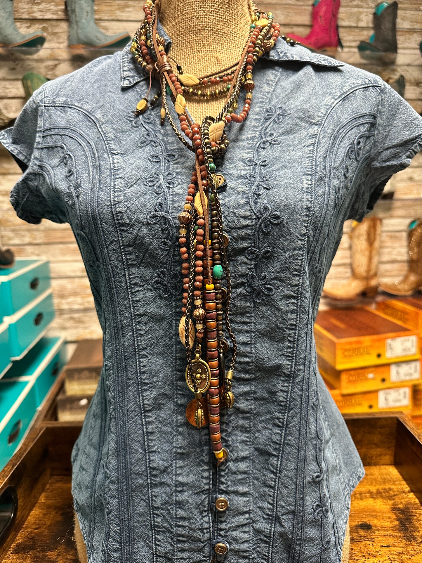 Blue denim shirt with jewelry on a mannequin.