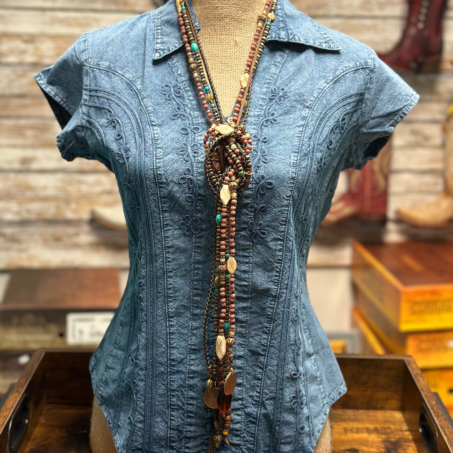 Blue denim shirt with long beaded necklace.