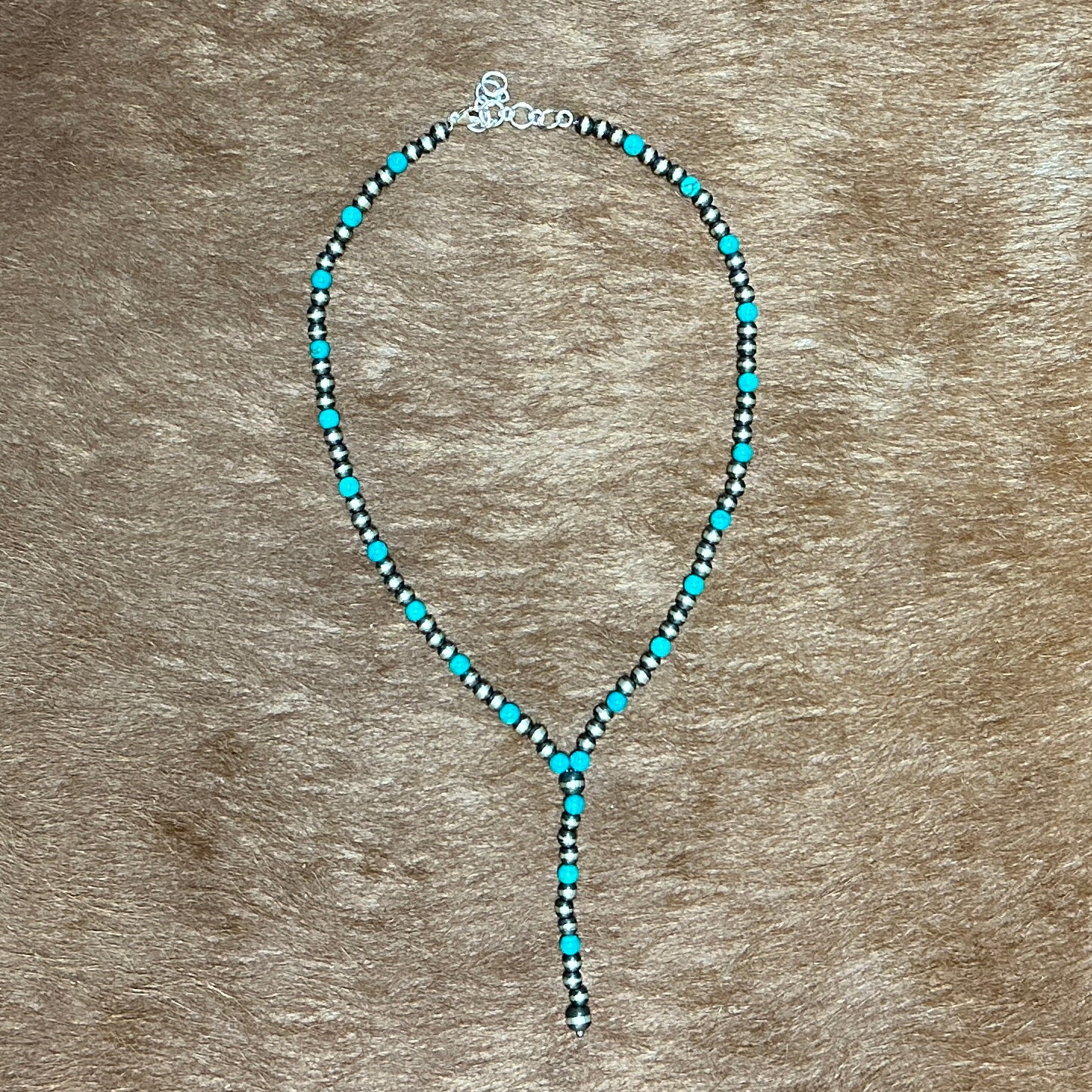 Necklace with turquoise beads on a brown background.