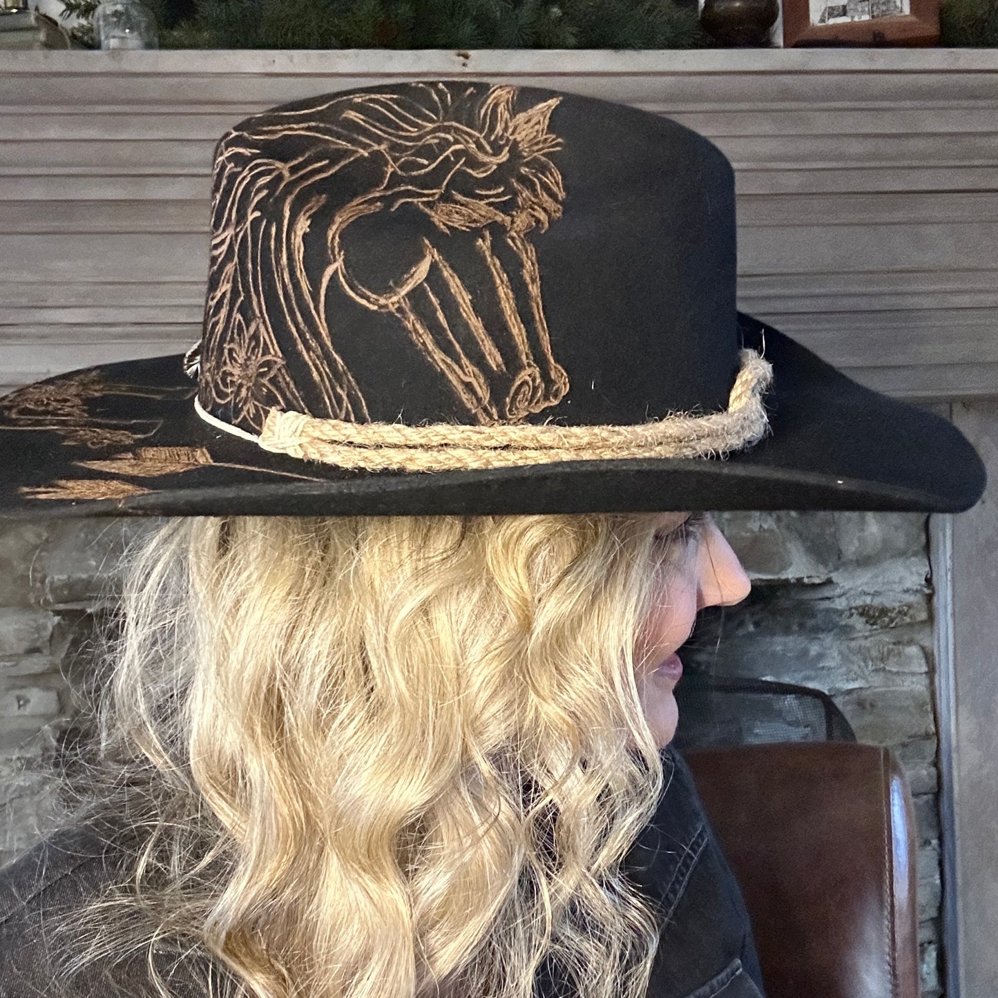 Woman wearing a black cowboy hat with a horse design.