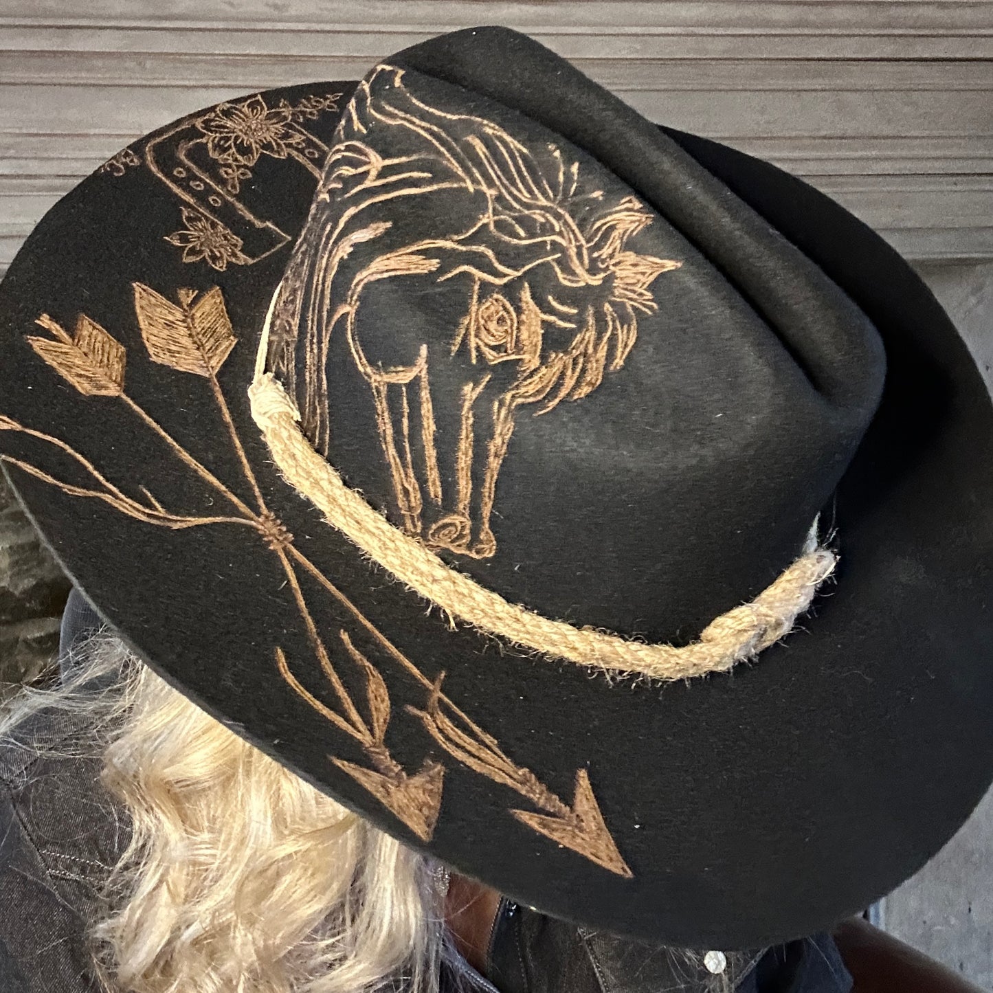 Black cowboy hat with horse and arrow designs.