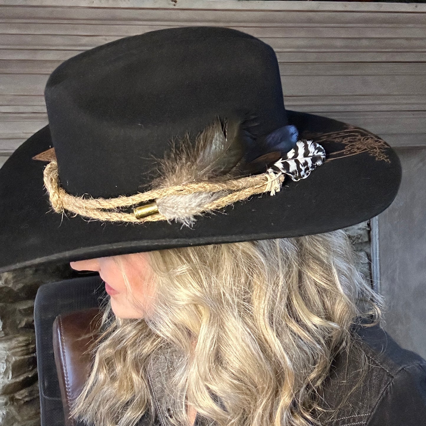 Woman wearing a black cowboy hat with rope and feathers.