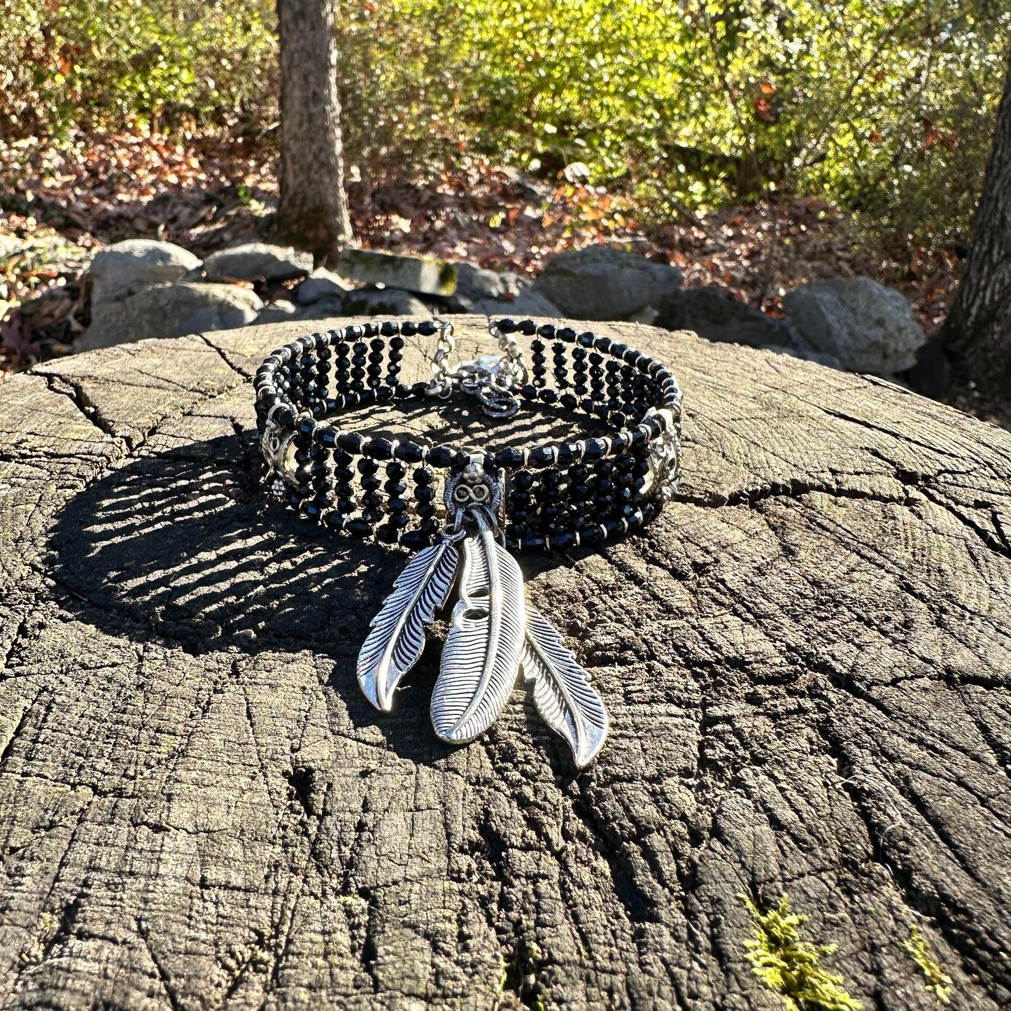 Black beaded bracelet with feather charms.