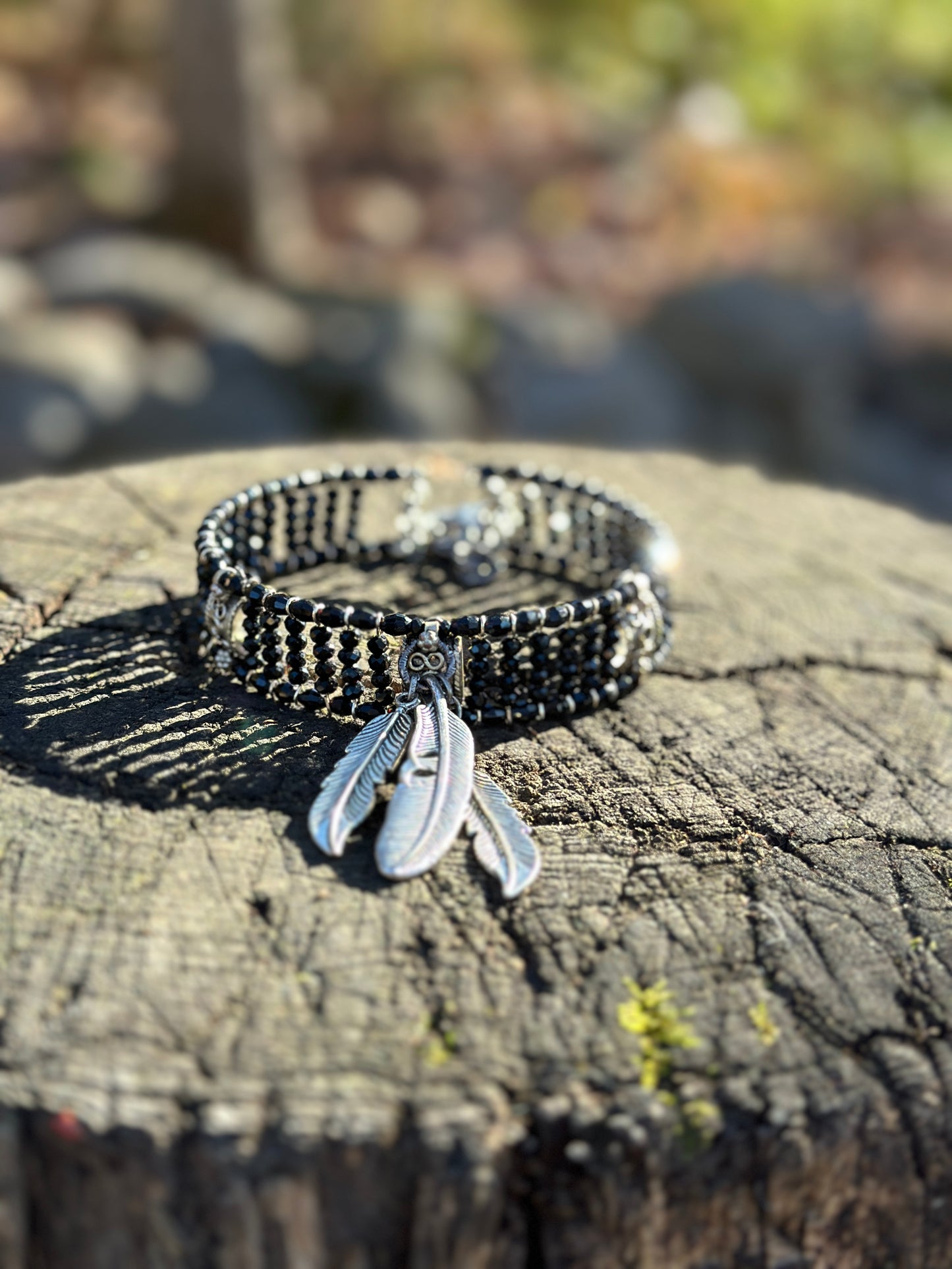 Black beaded bracelet with feather charm.