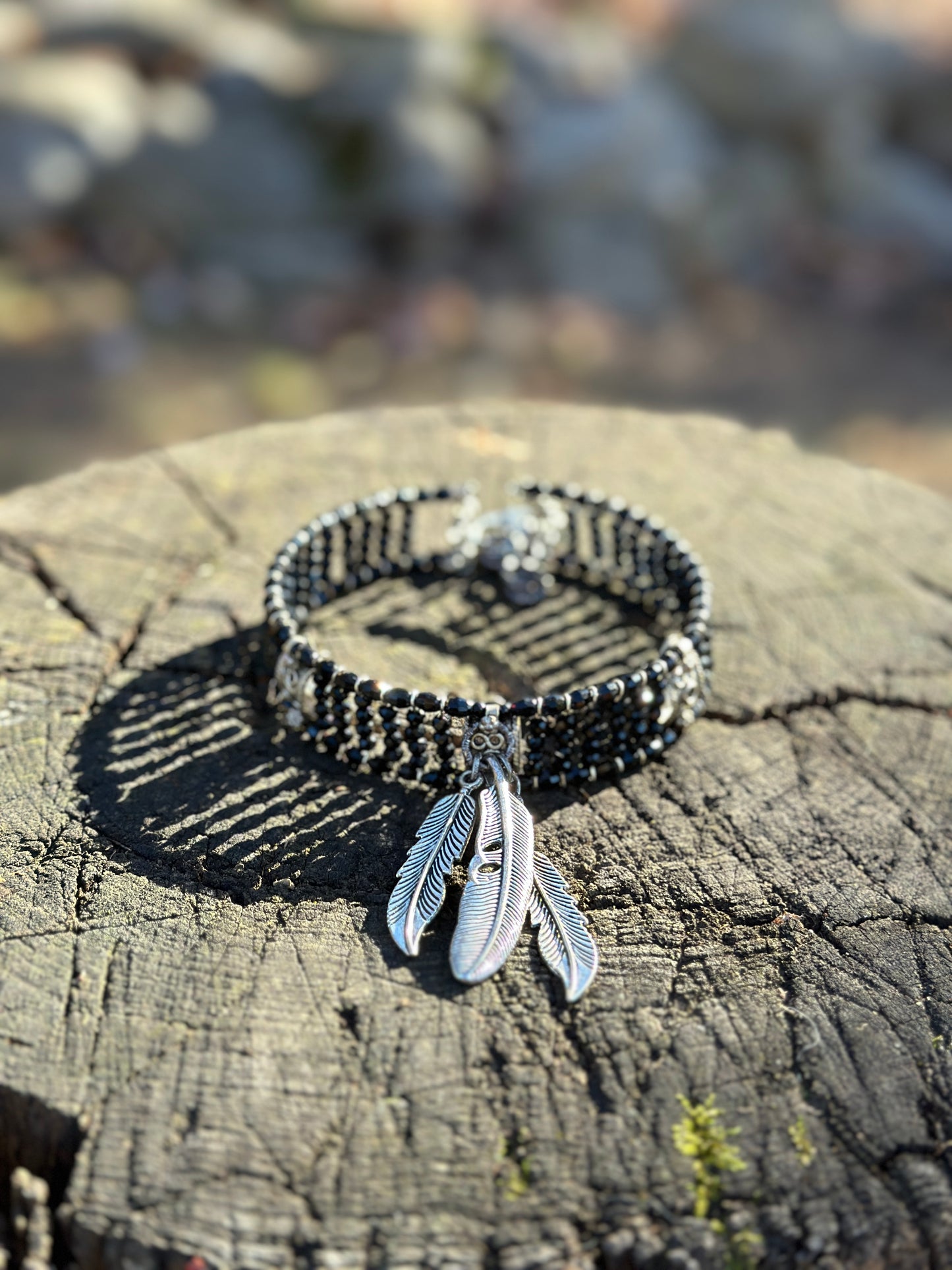 Black bracelet with silver feather charms.