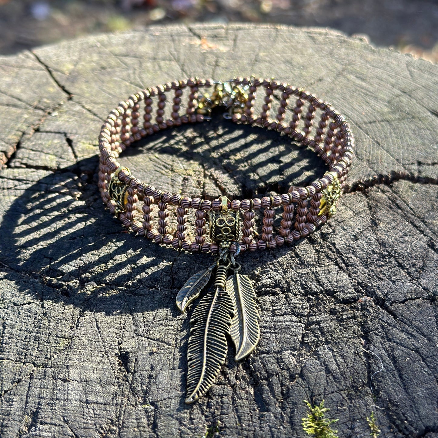Brown beaded collar with feather charm.