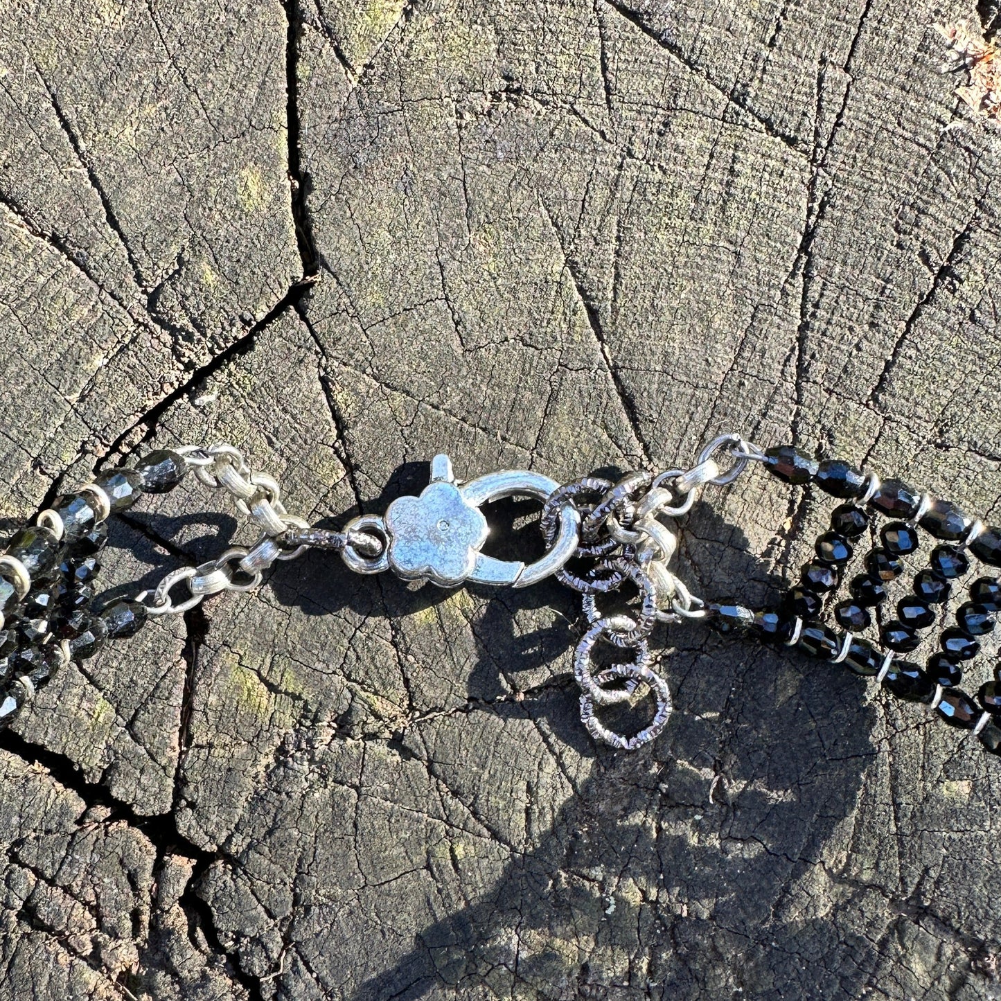 Close-up of a black beaded necklace clasp on a wood surface.