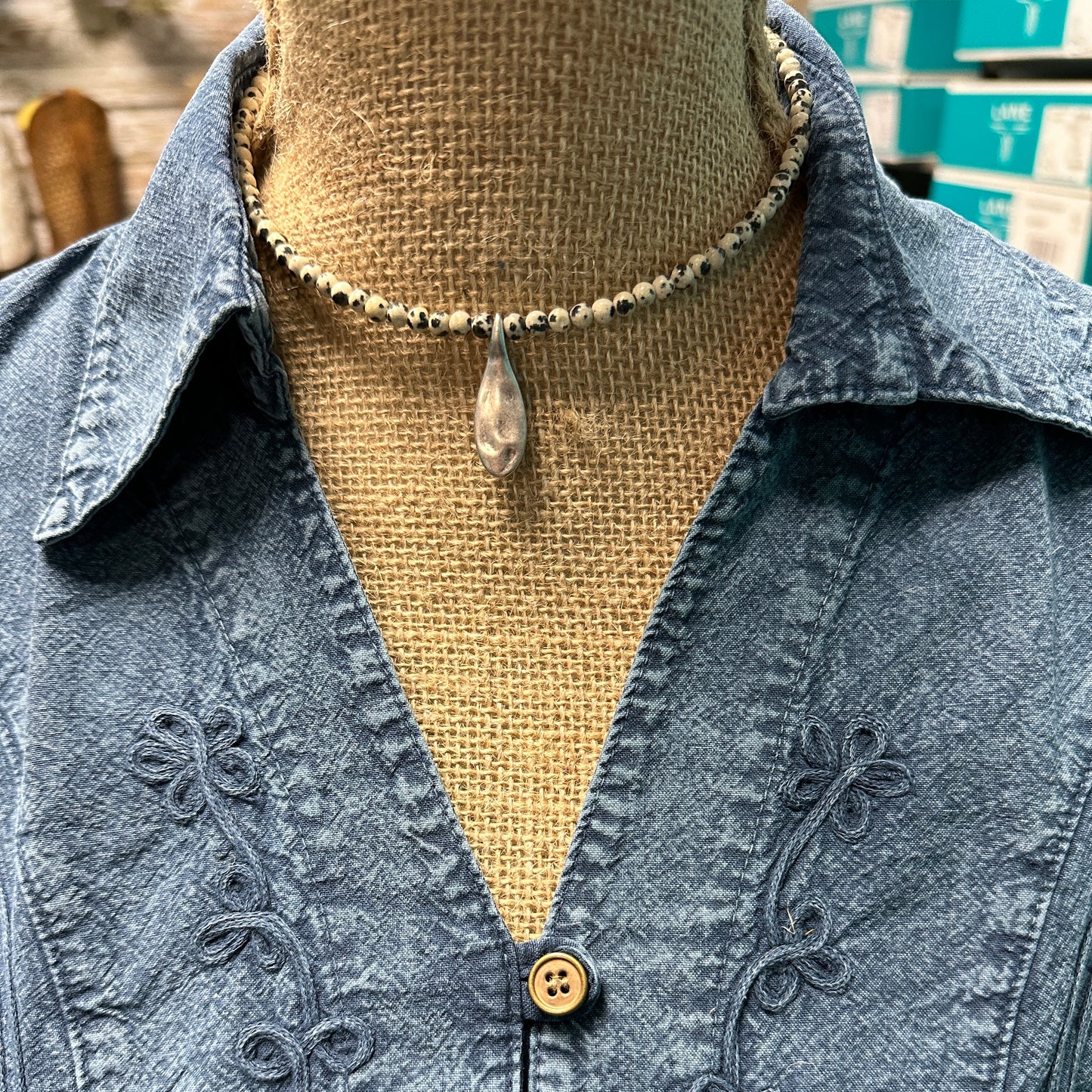 Necklace with pendant on a denim shirt.