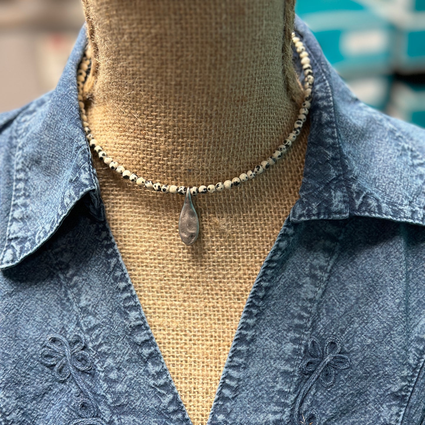 Necklace with pendant on denim shirt.
