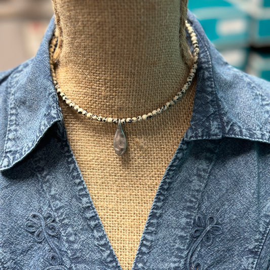 Necklace with pendant on denim shirt.
