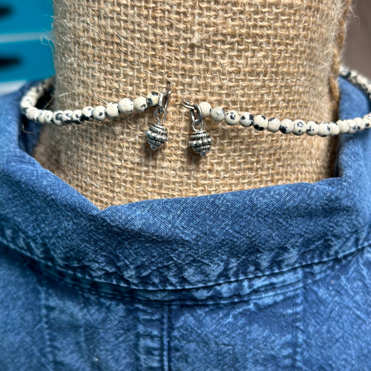 Necklace clasp and beads on blue shirt.
