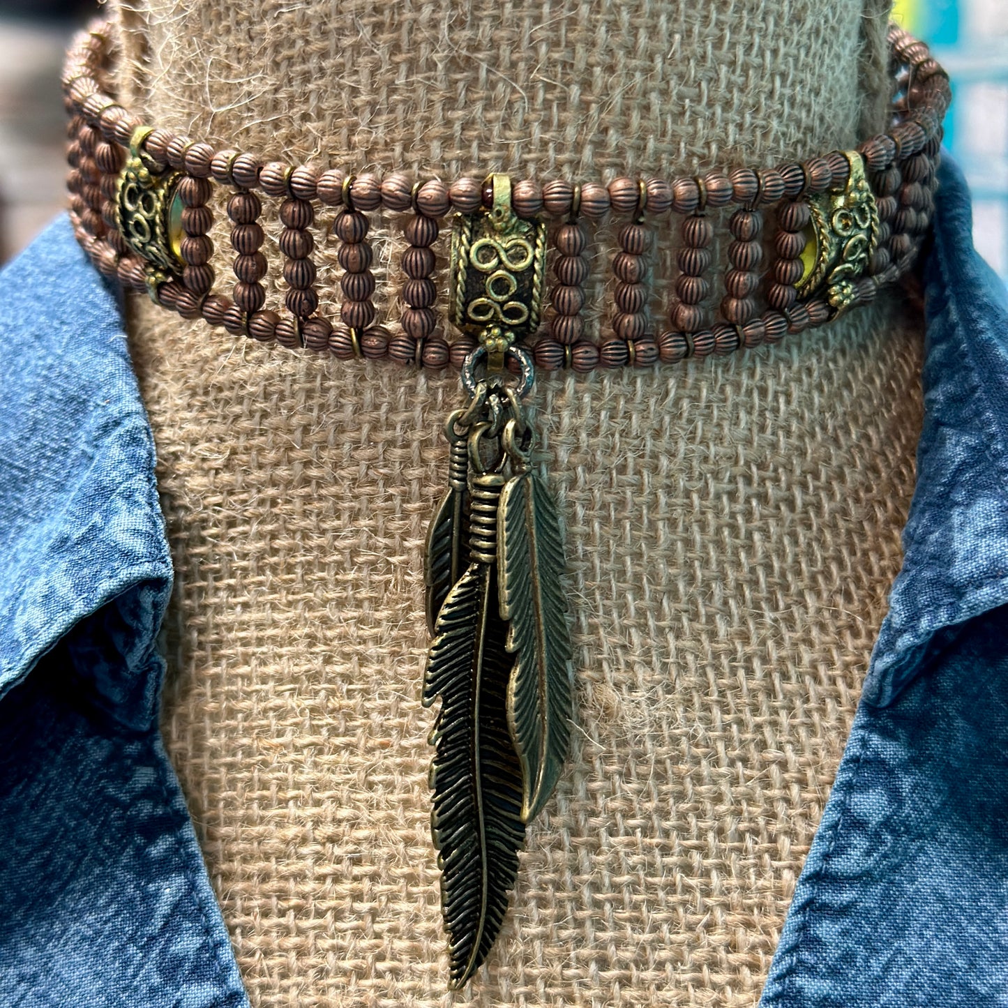 Bronze choker necklace with feather pendant.