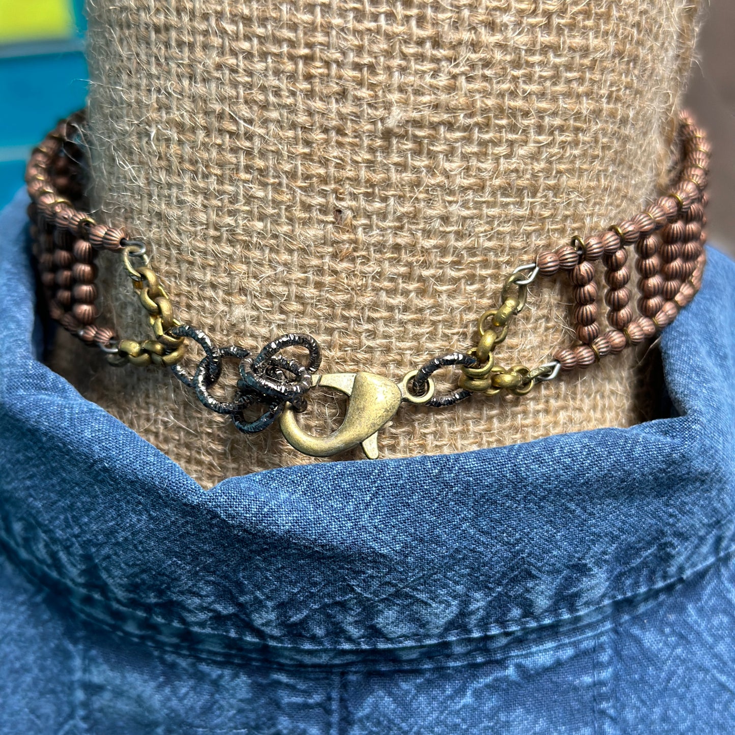 Bronze necklace clasp on denim shirt.