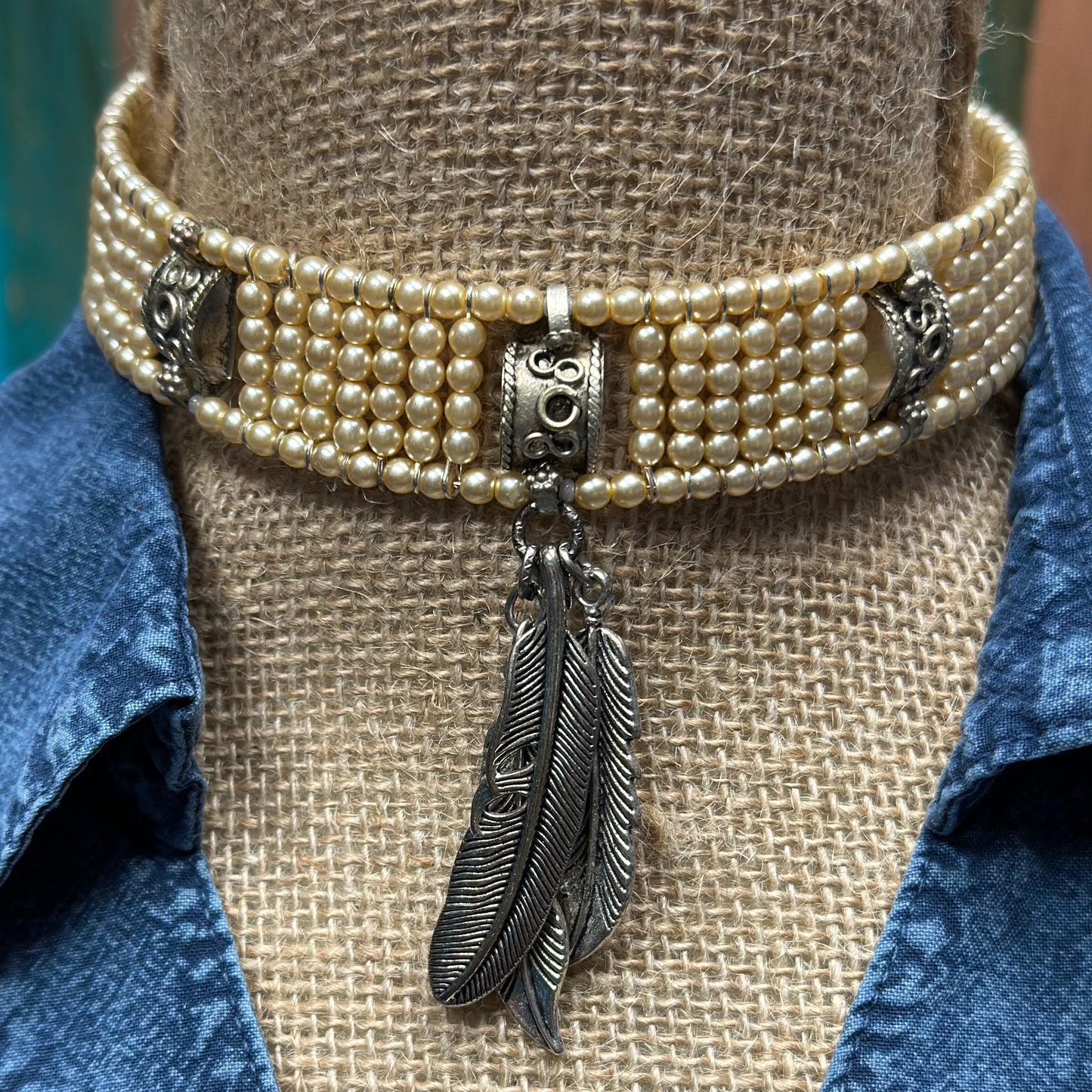 Pearl choker necklace with feather charm.