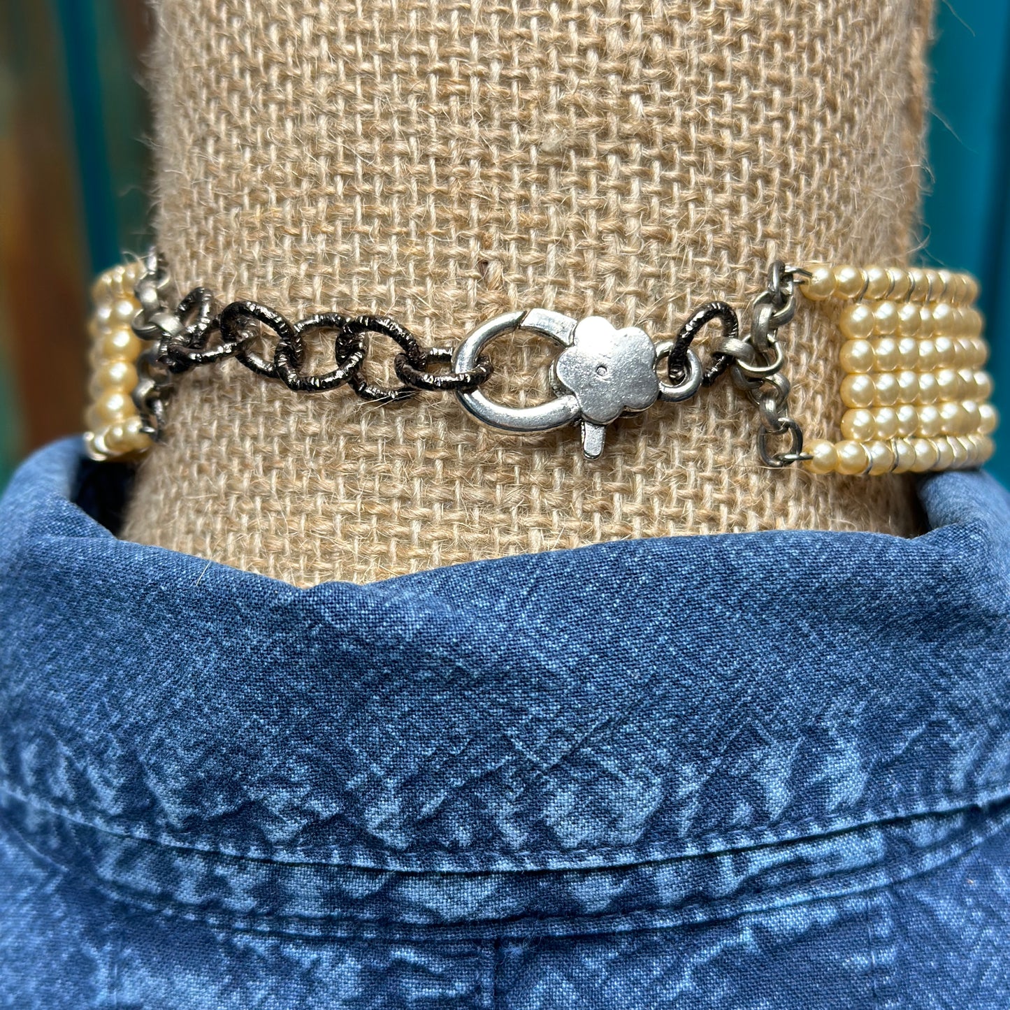 Pearl choker necklace on denim shirt.