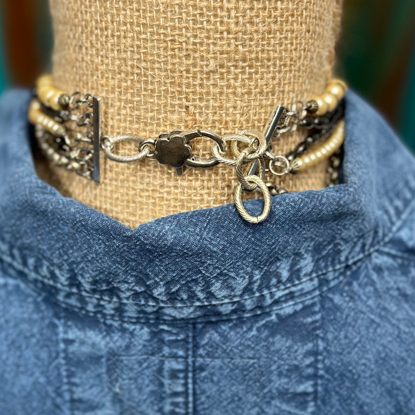Necklace with multiple strands on denim shirt.