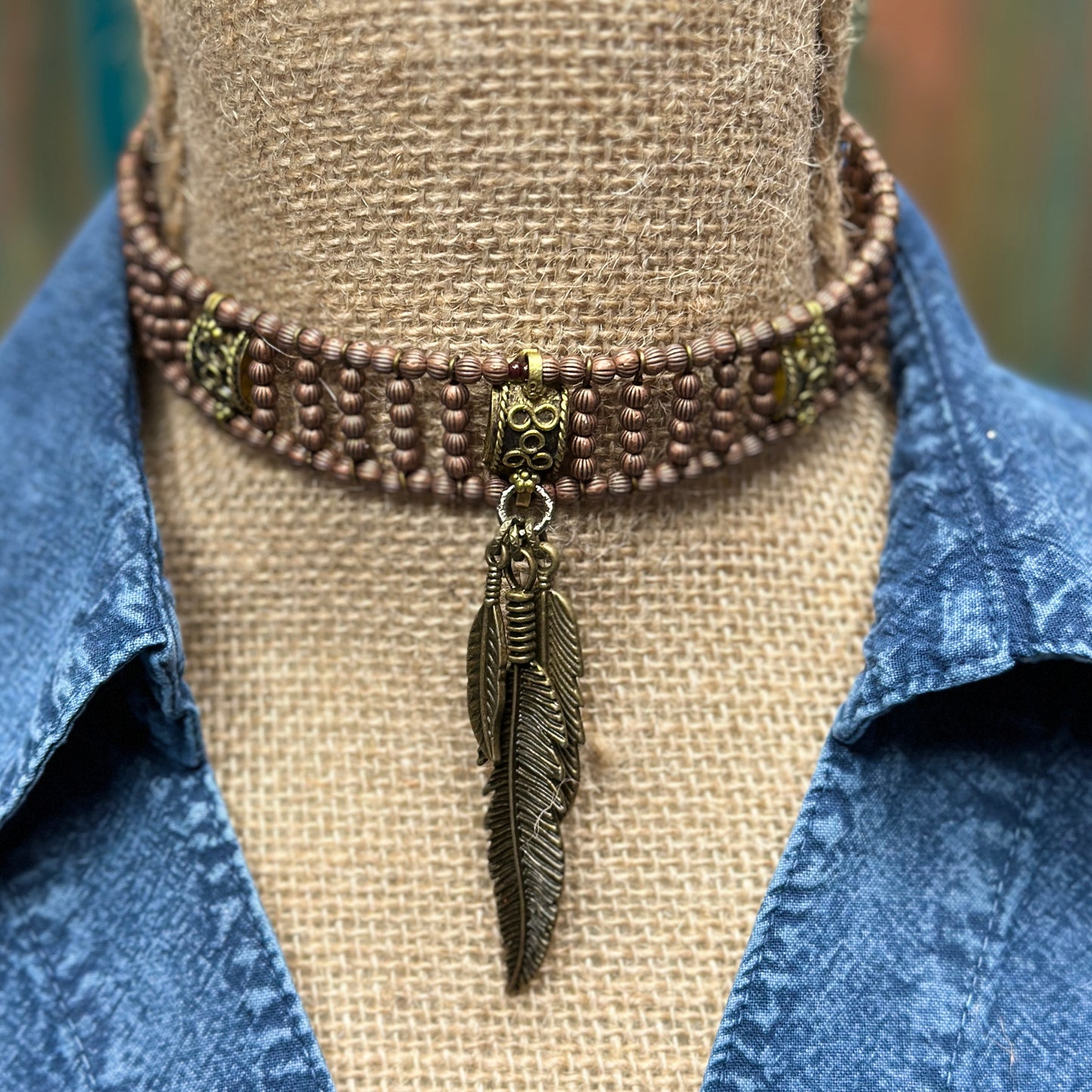 Brown beaded choker necklace with feather charm.