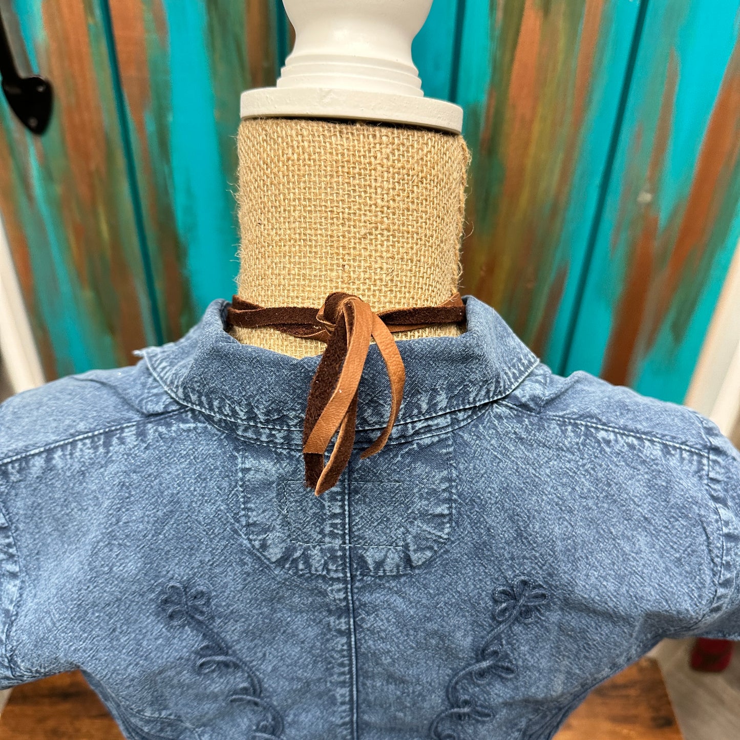 Mannequin wearing denim jacket and brown choker.