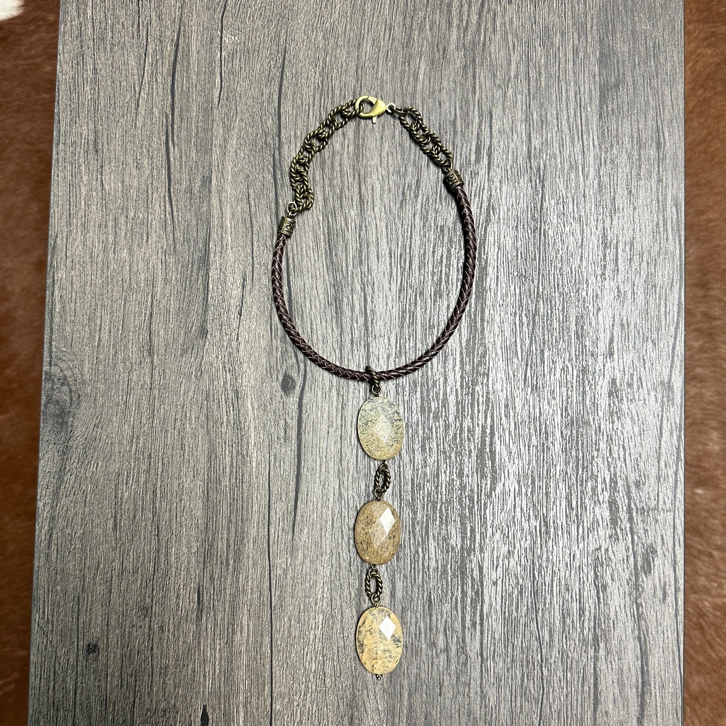 Braided leather necklace with pendant of three stones.