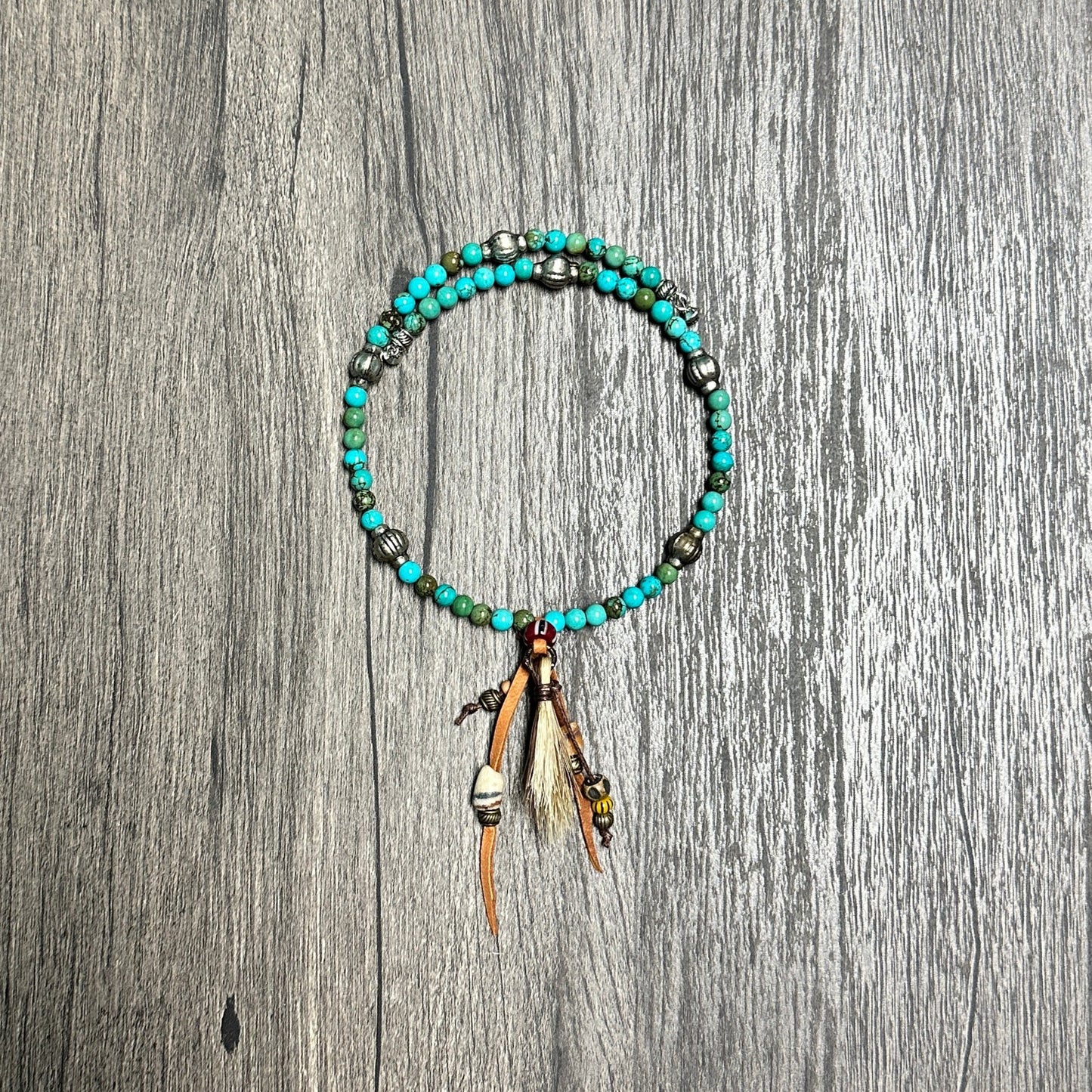 Turquoise beaded bracelet with feather charms.