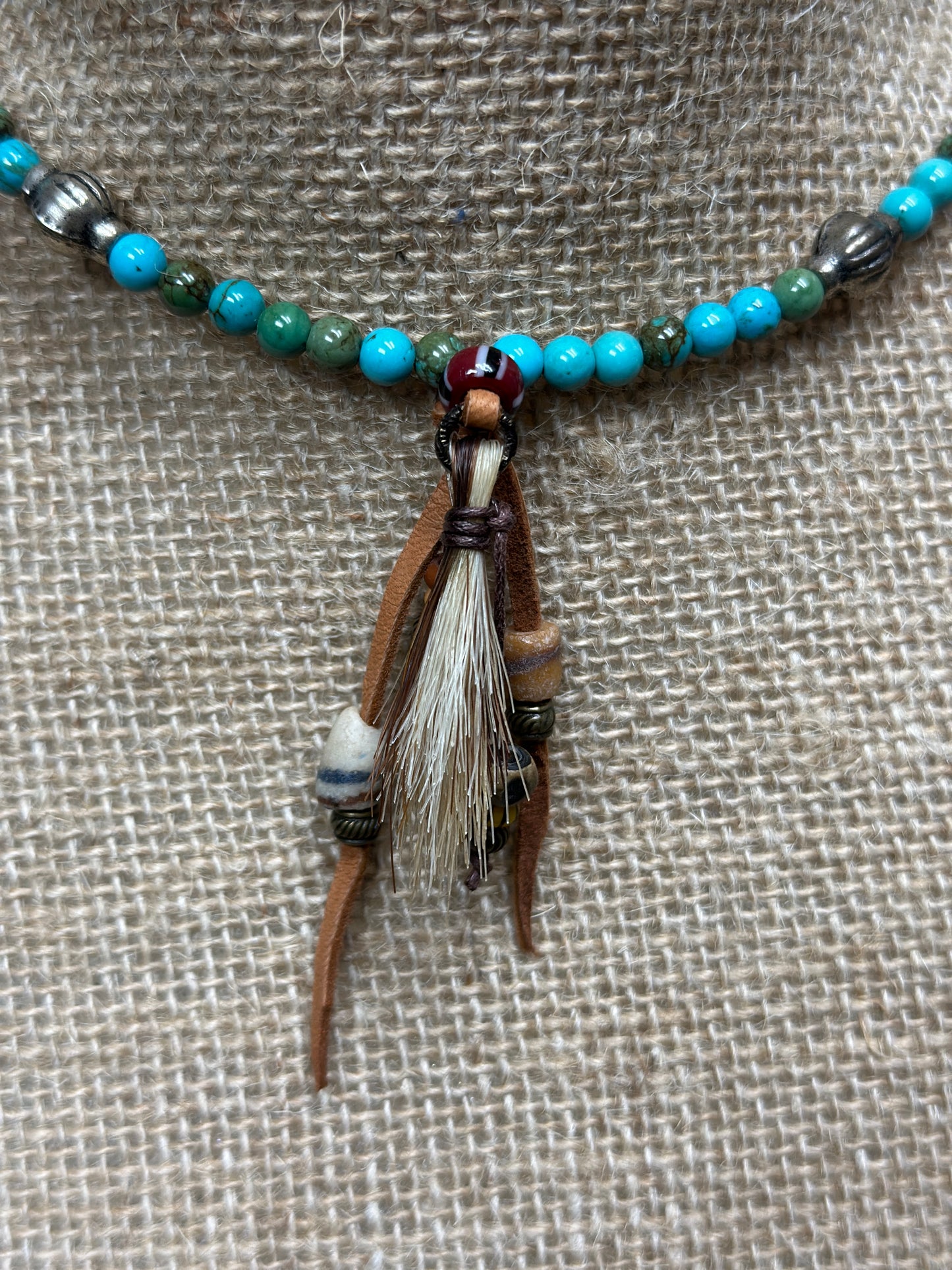 Necklace with turquoise beads and leather pendant.