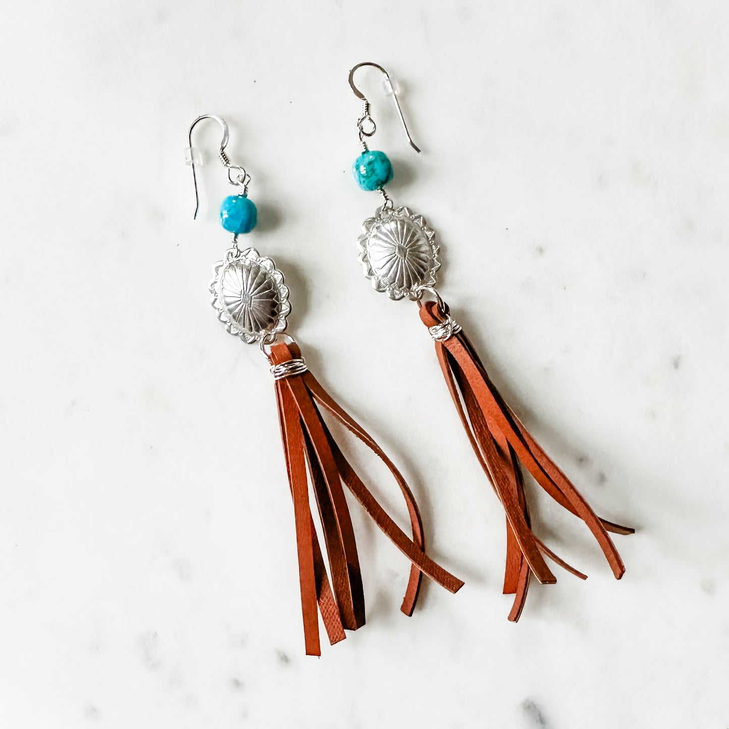 Earrings with turquoise beads, silver details, and leather tassels.