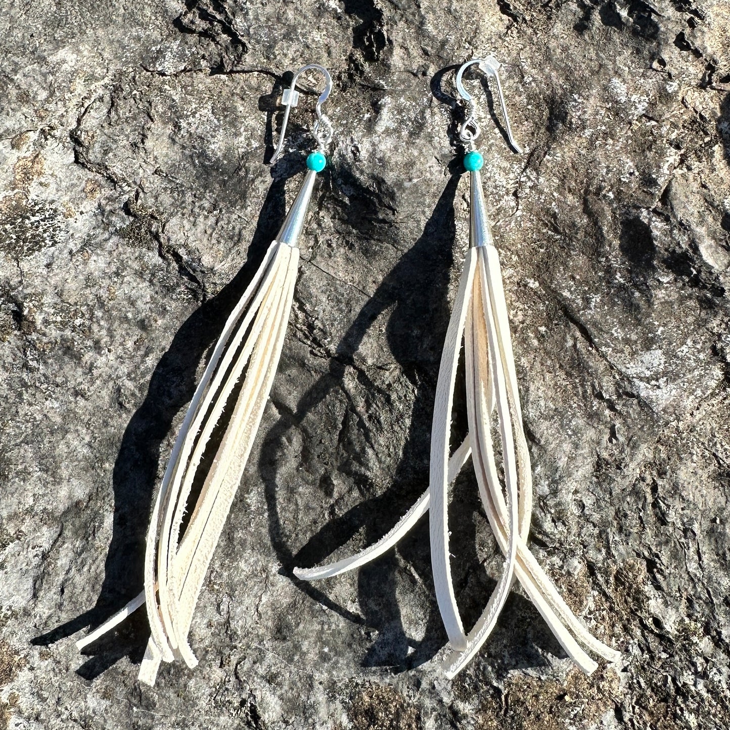 White leather fringe earrings with turquoise accents.