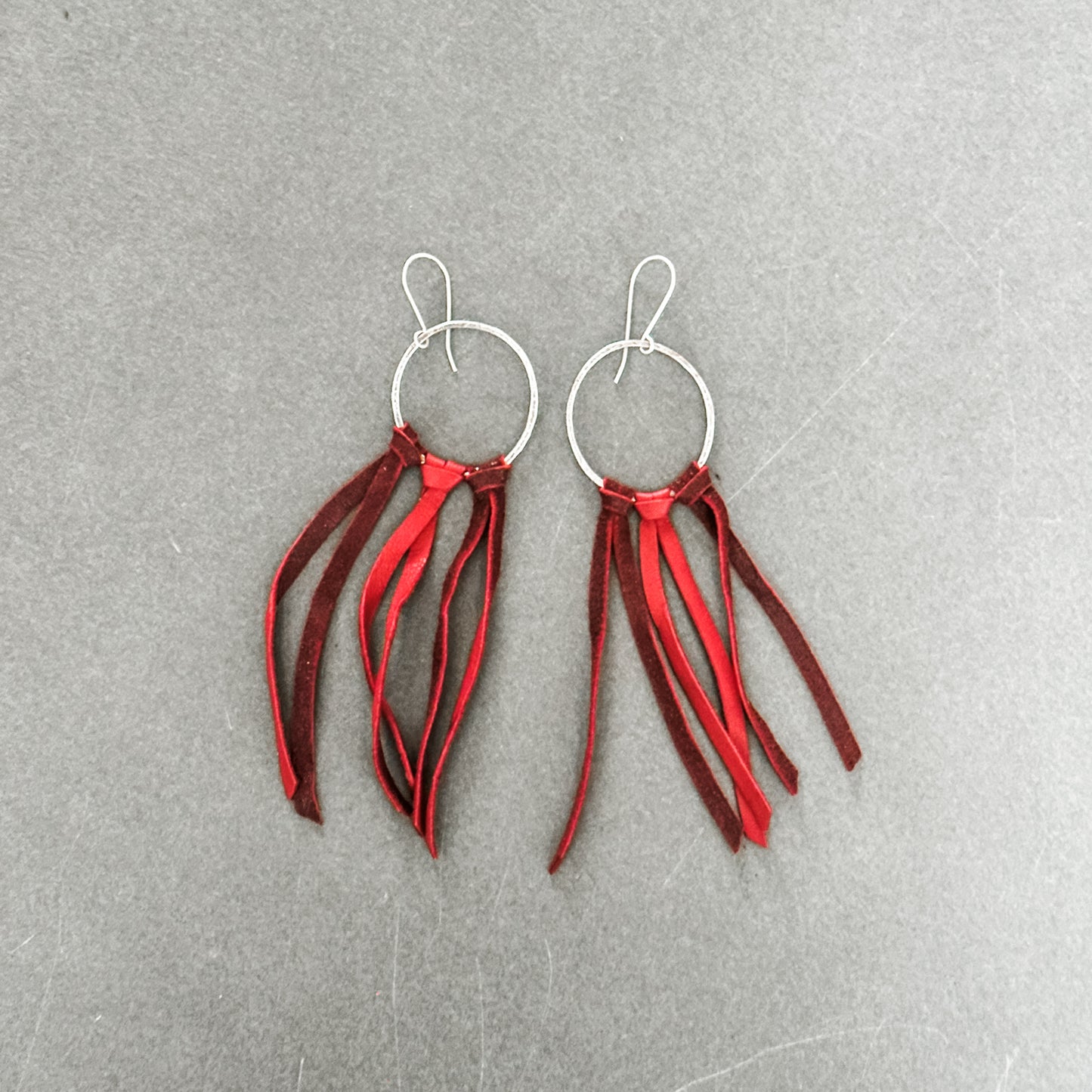 Pair of silver hoop earrings with red and burgundy fringe.