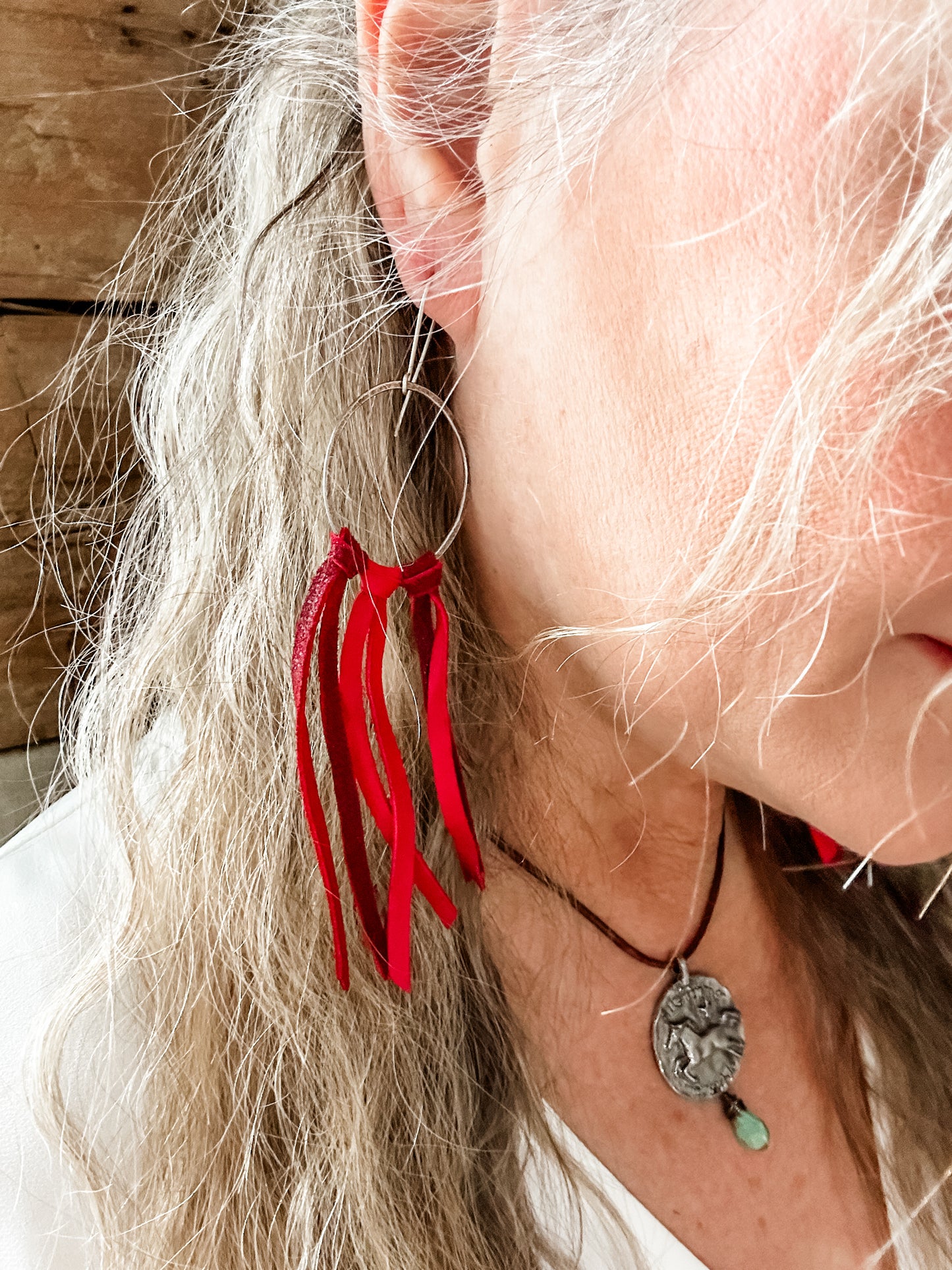 Woman with red fringe earrings and necklace.