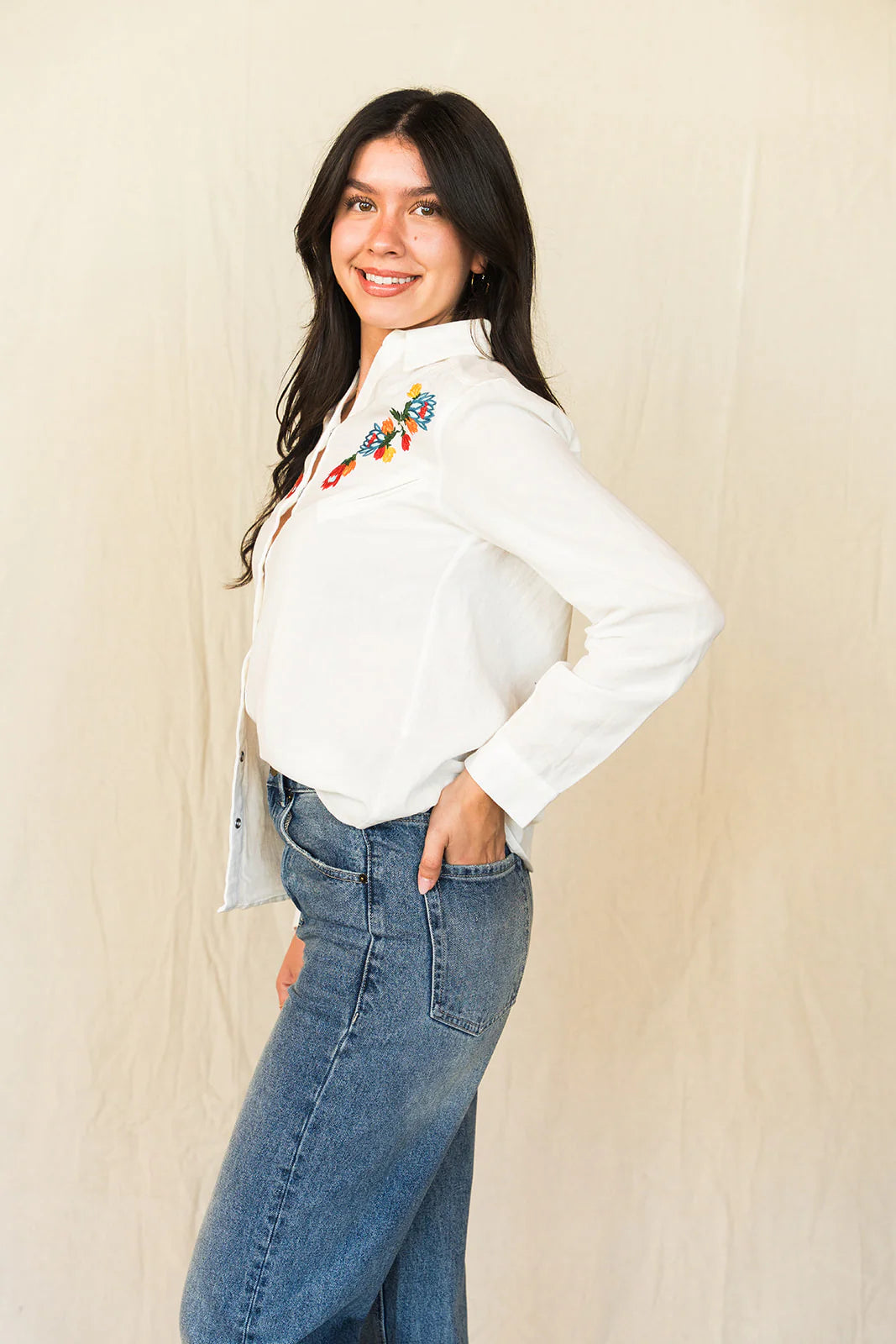 Woman in Whiskey Apparel white embroidered shirt and jeans.