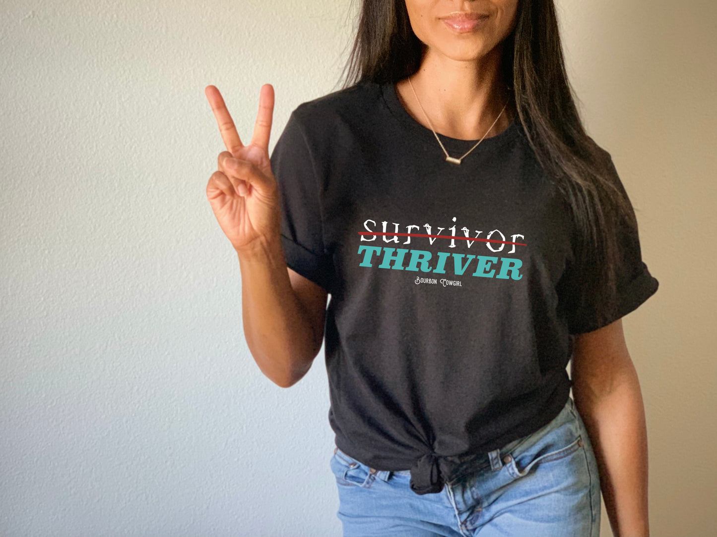 Woman in Survivor Thriver tee showing peace sign