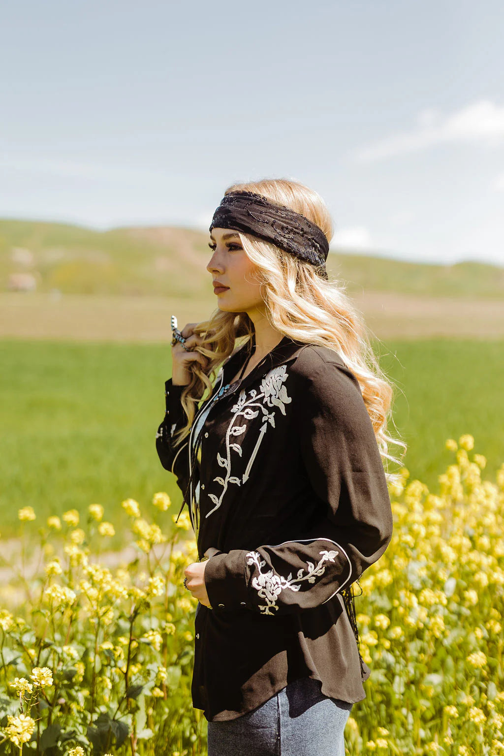 Woman in black shirt, WESTERNWILDFLOWER, in field of yellow flowers.