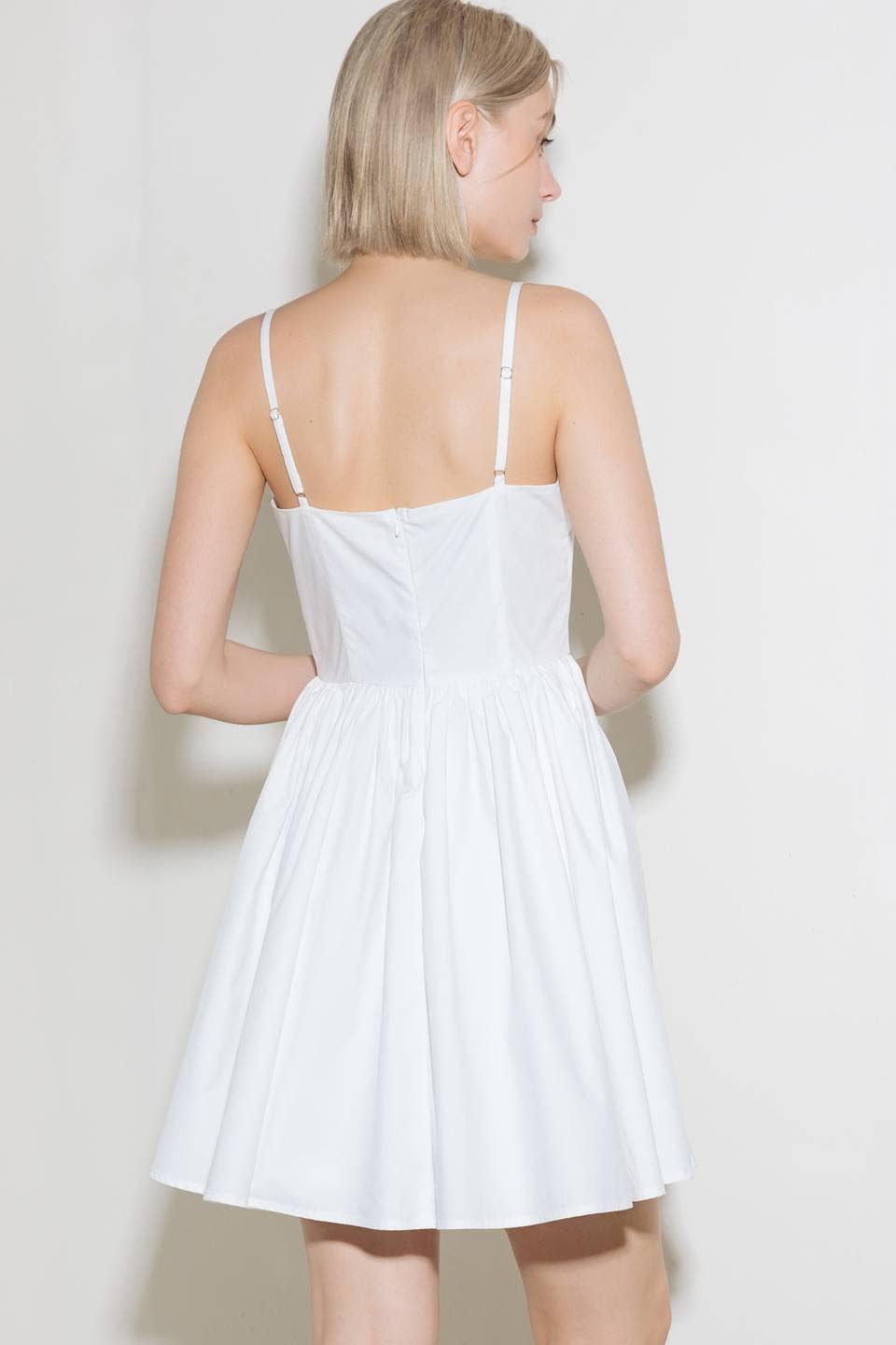 Woman wearing a white sundress, viewed from the back.