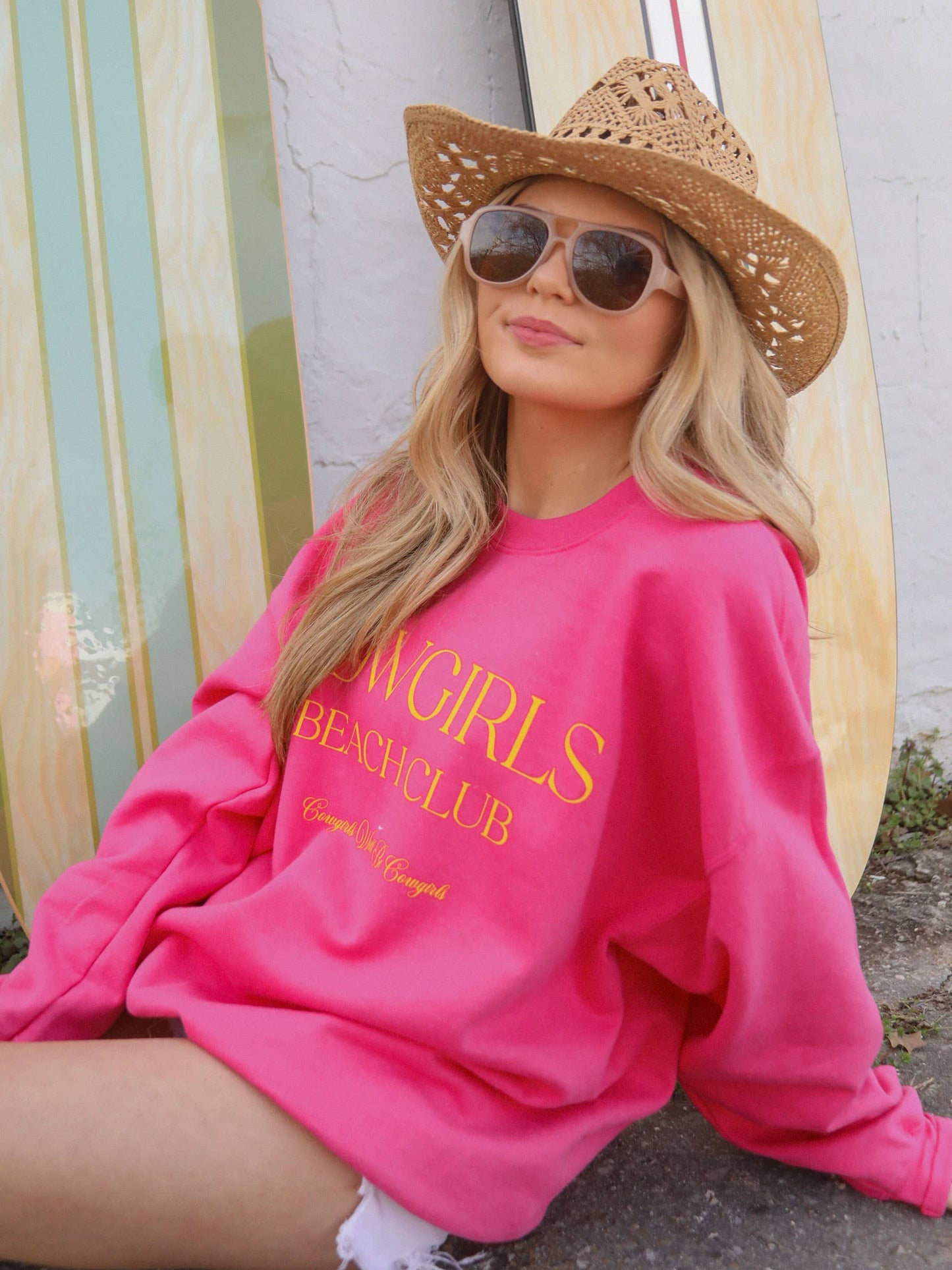 Woman in pink sweatshirt, sunglasses, and hat.