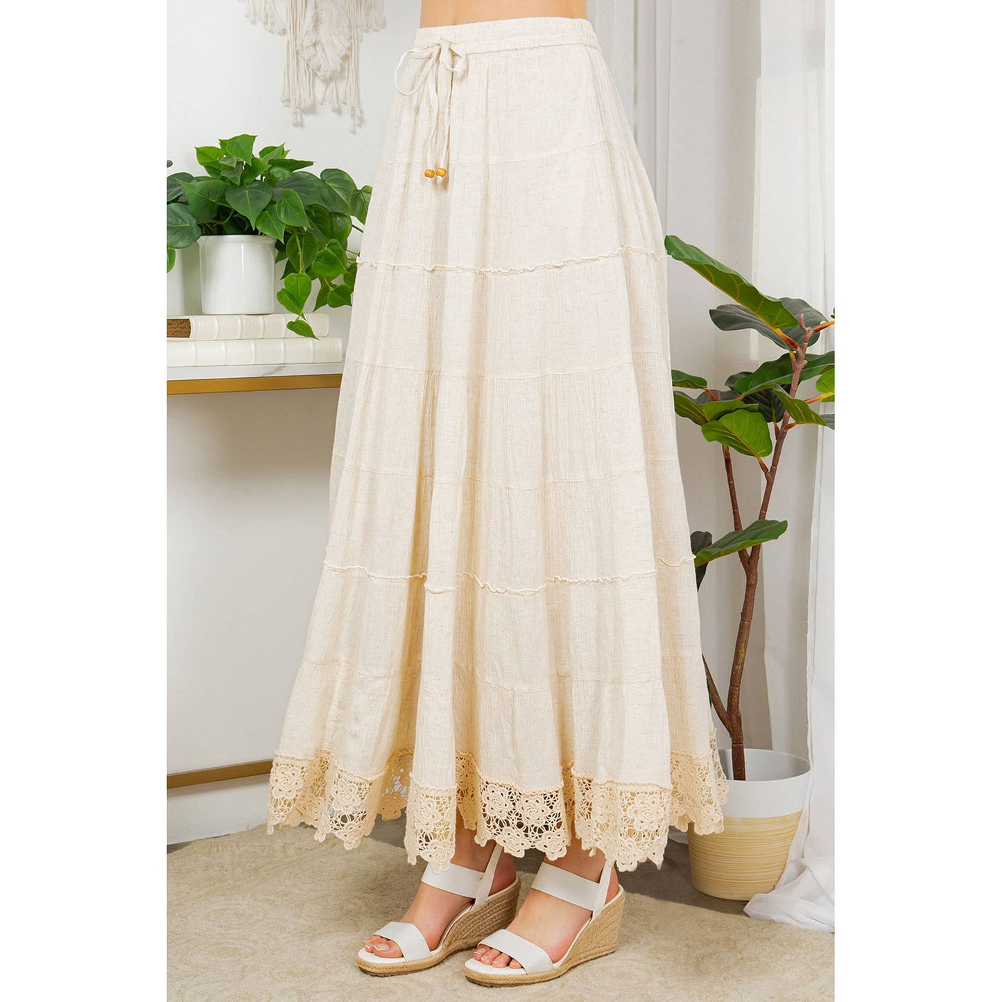 Cream-colored, tiered maxi skirt with lace hem, and white sandals.