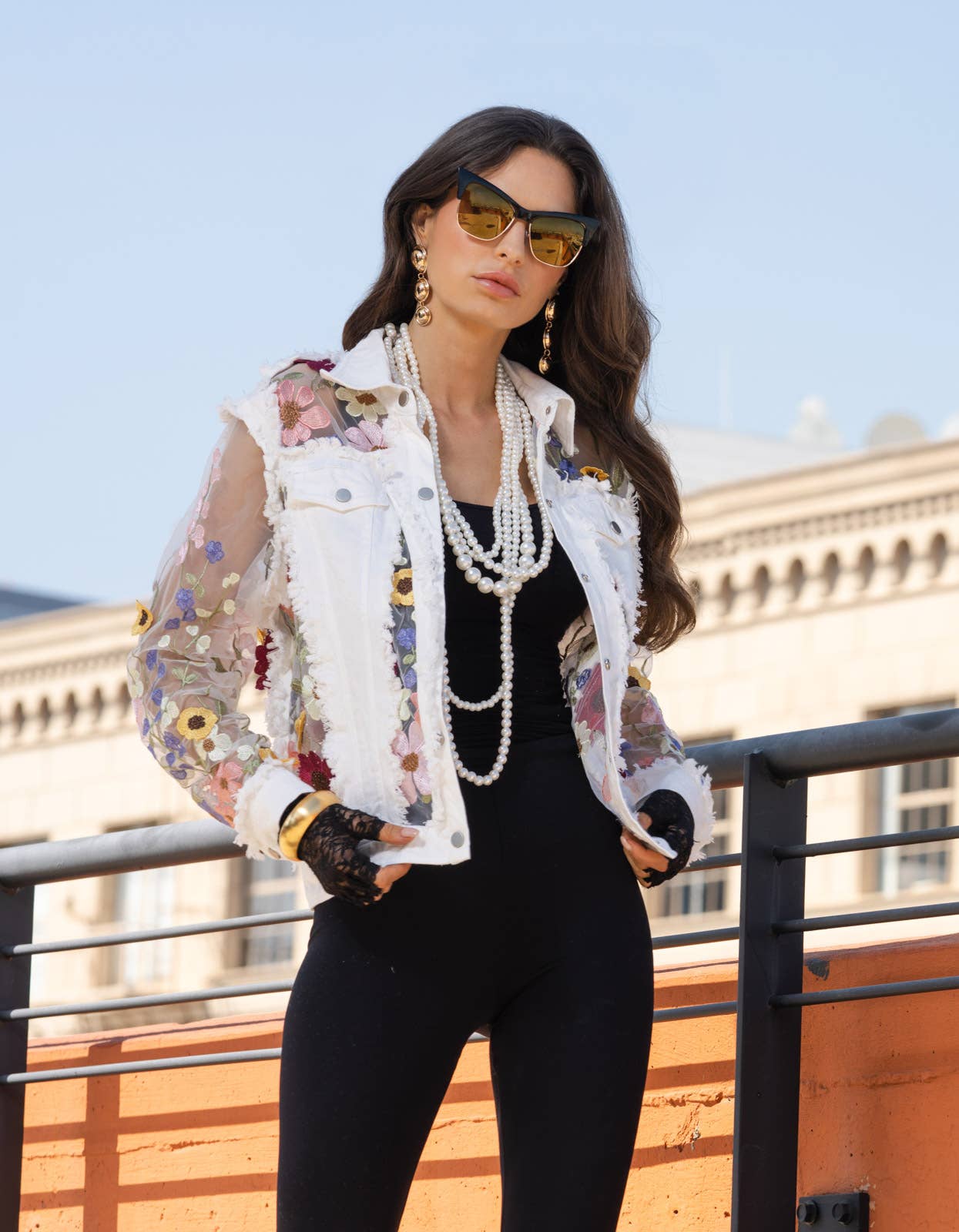 Woman in white floral jacket and sunglasses.