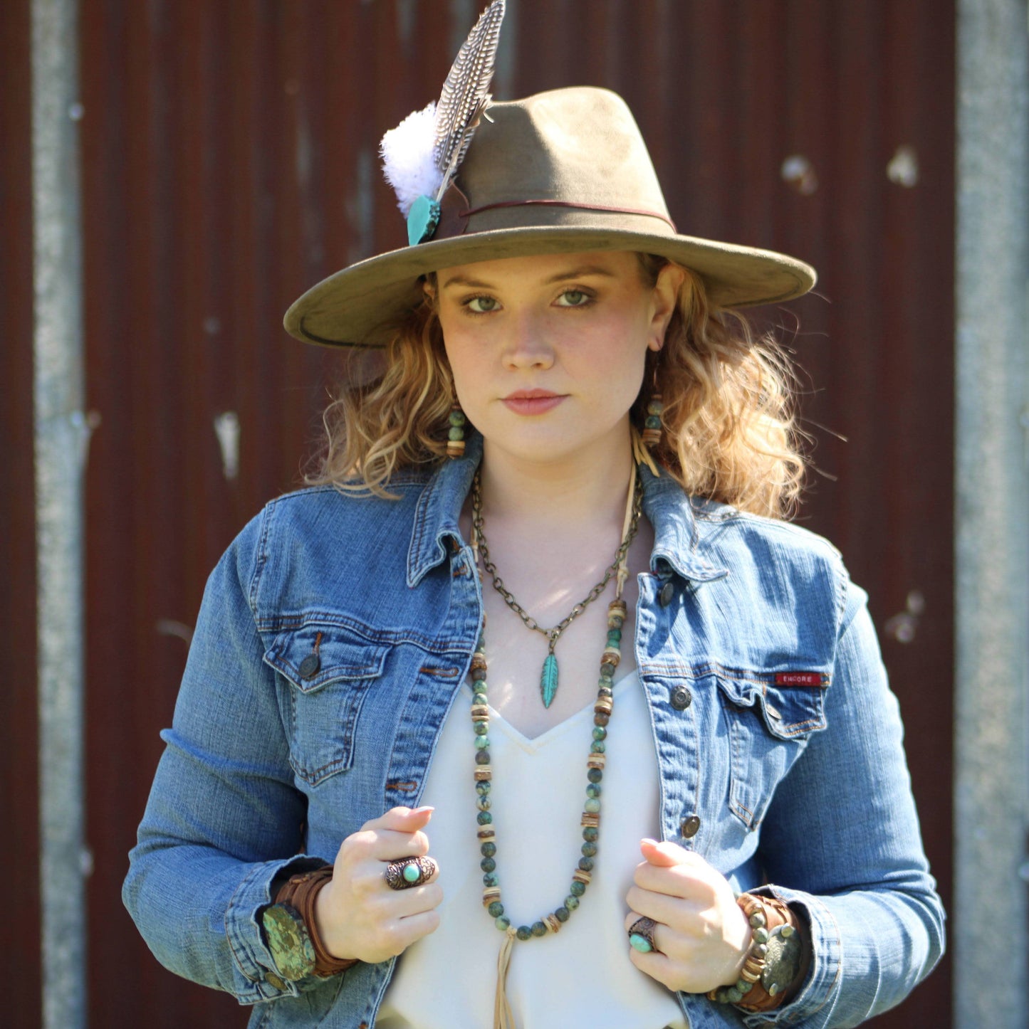 Woman in denim jacket and hat.