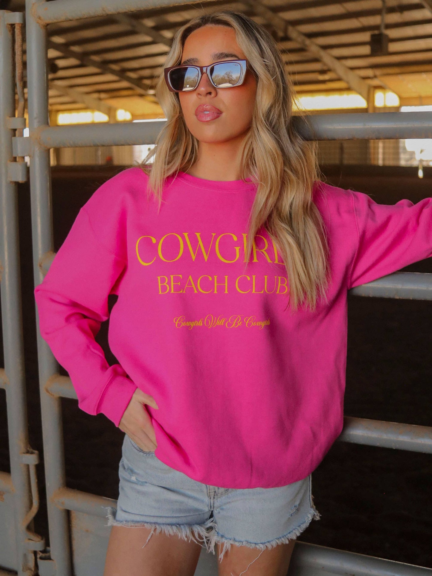 Woman in pink sweatshirt and sunglasses.