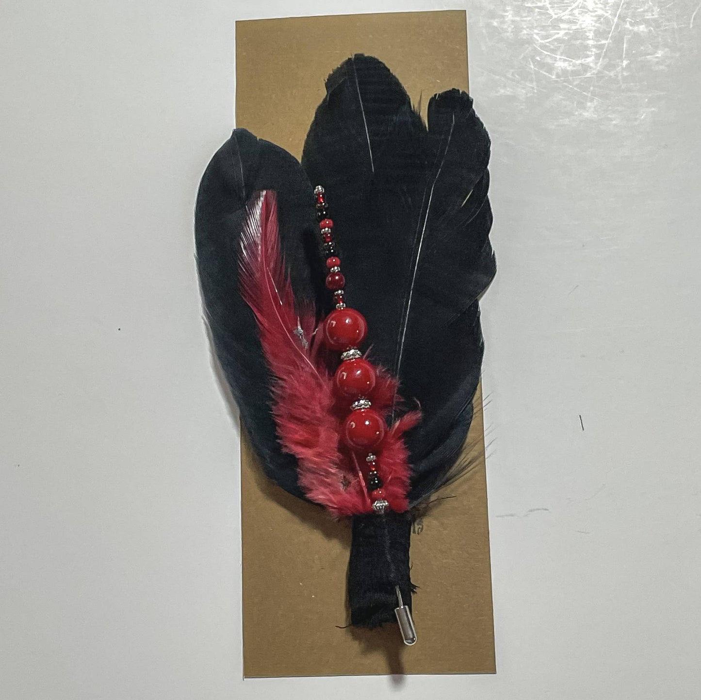 Black feather pin with red beads and feather.