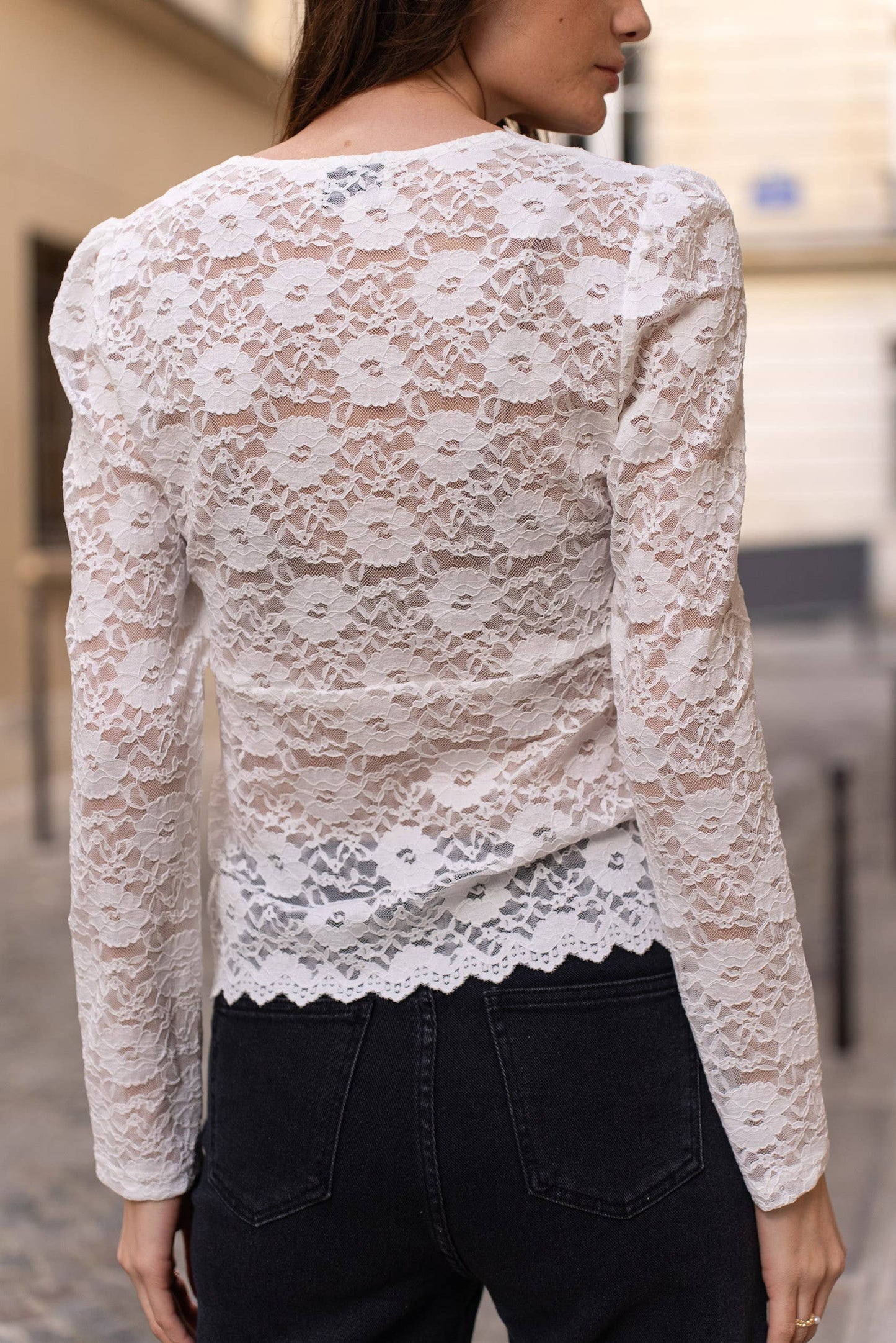 Woman in white lace top and black pants.